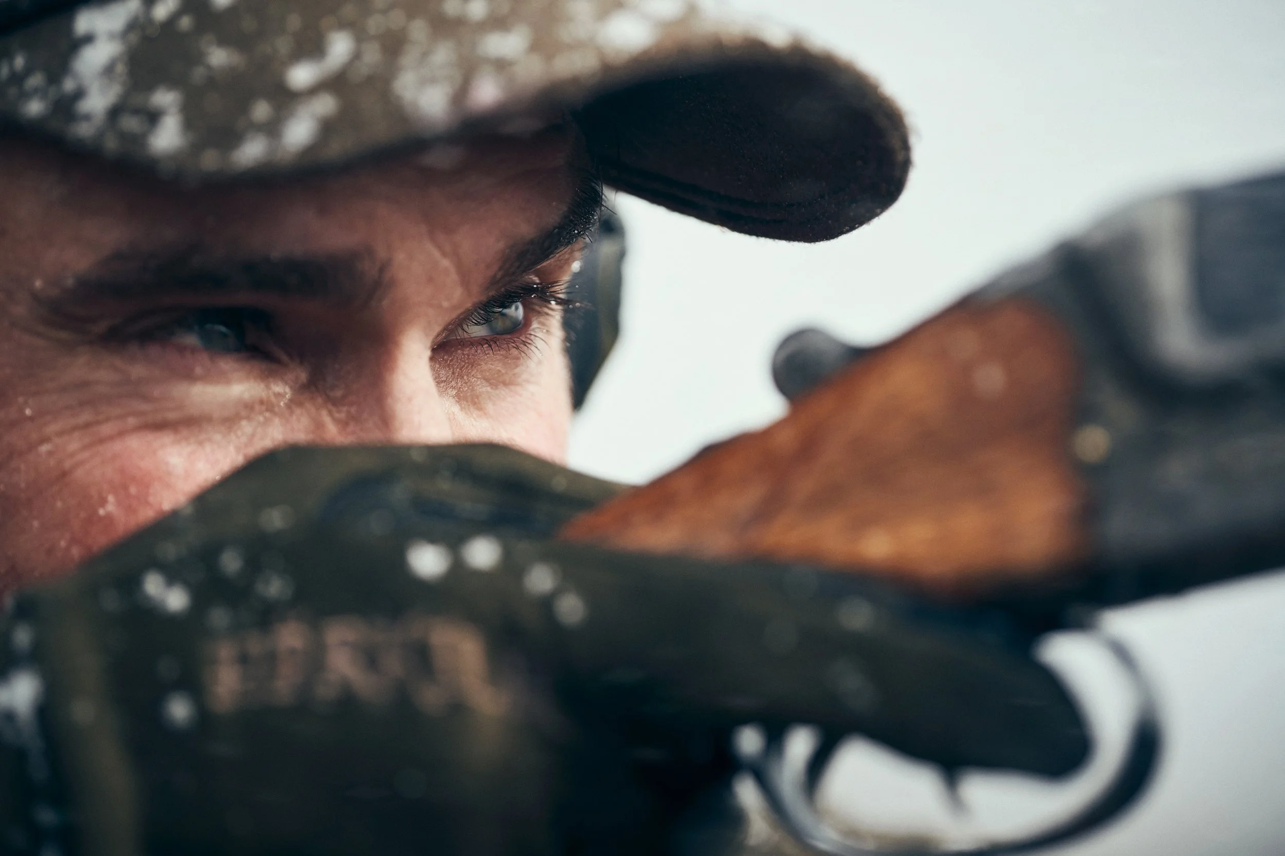 Close-up of hunter aiming rifle, focus on eye and weapon alignment
