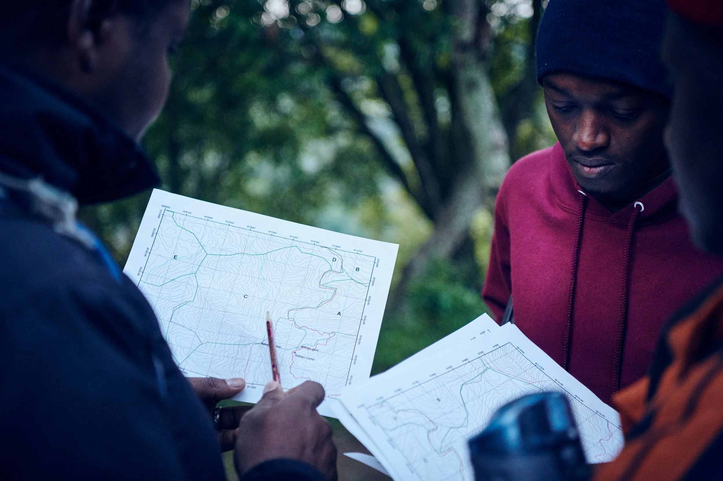 Two field workers studying map together, planning route in forest environment