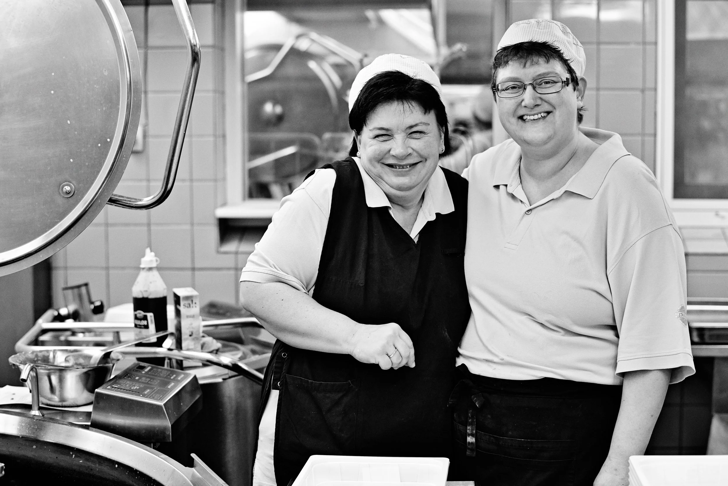 Two kitchen workers standing together in kitchen, smiling portrait