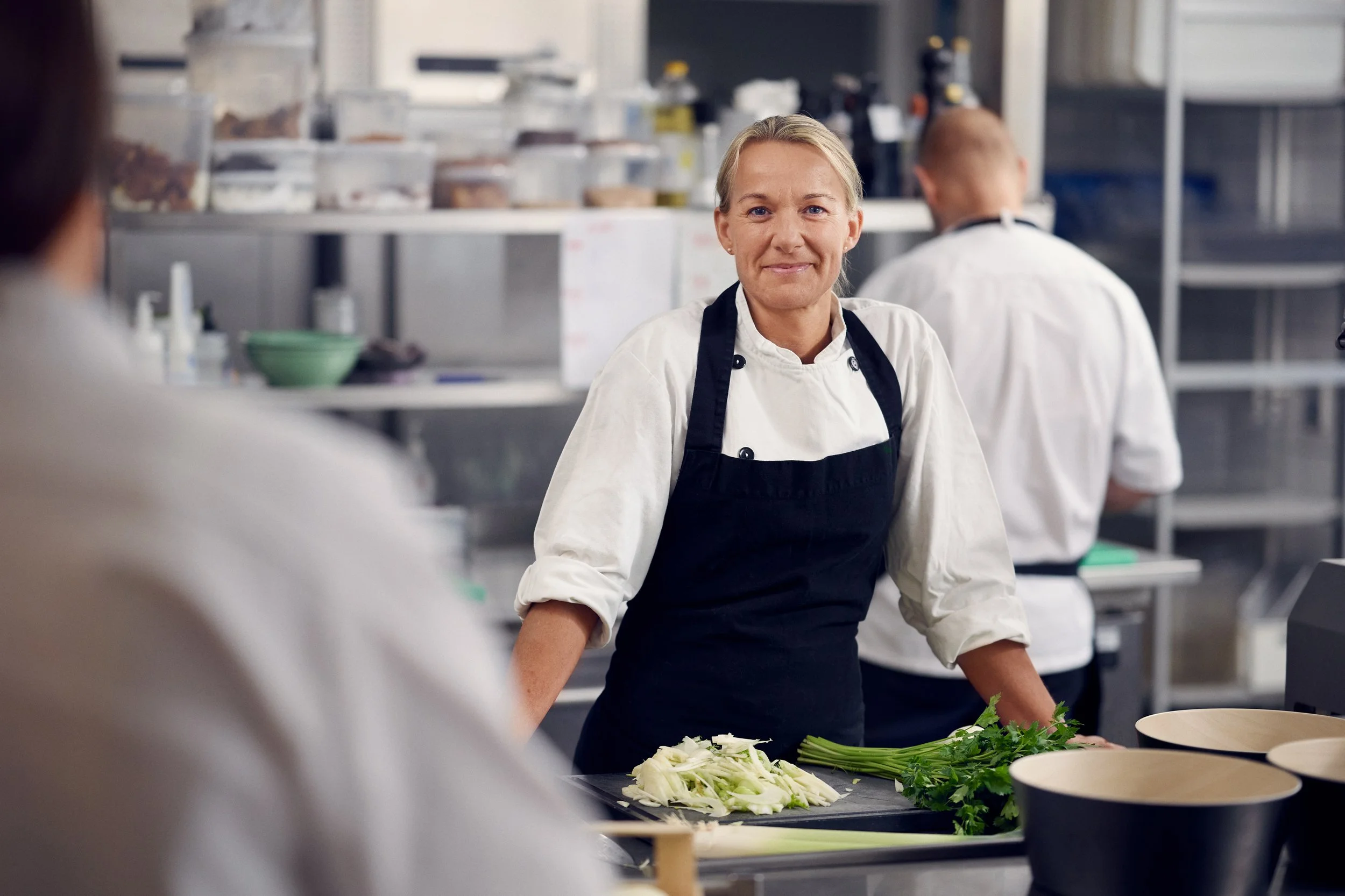 Chef standing in kitchen preparing vegetables, professional work environment