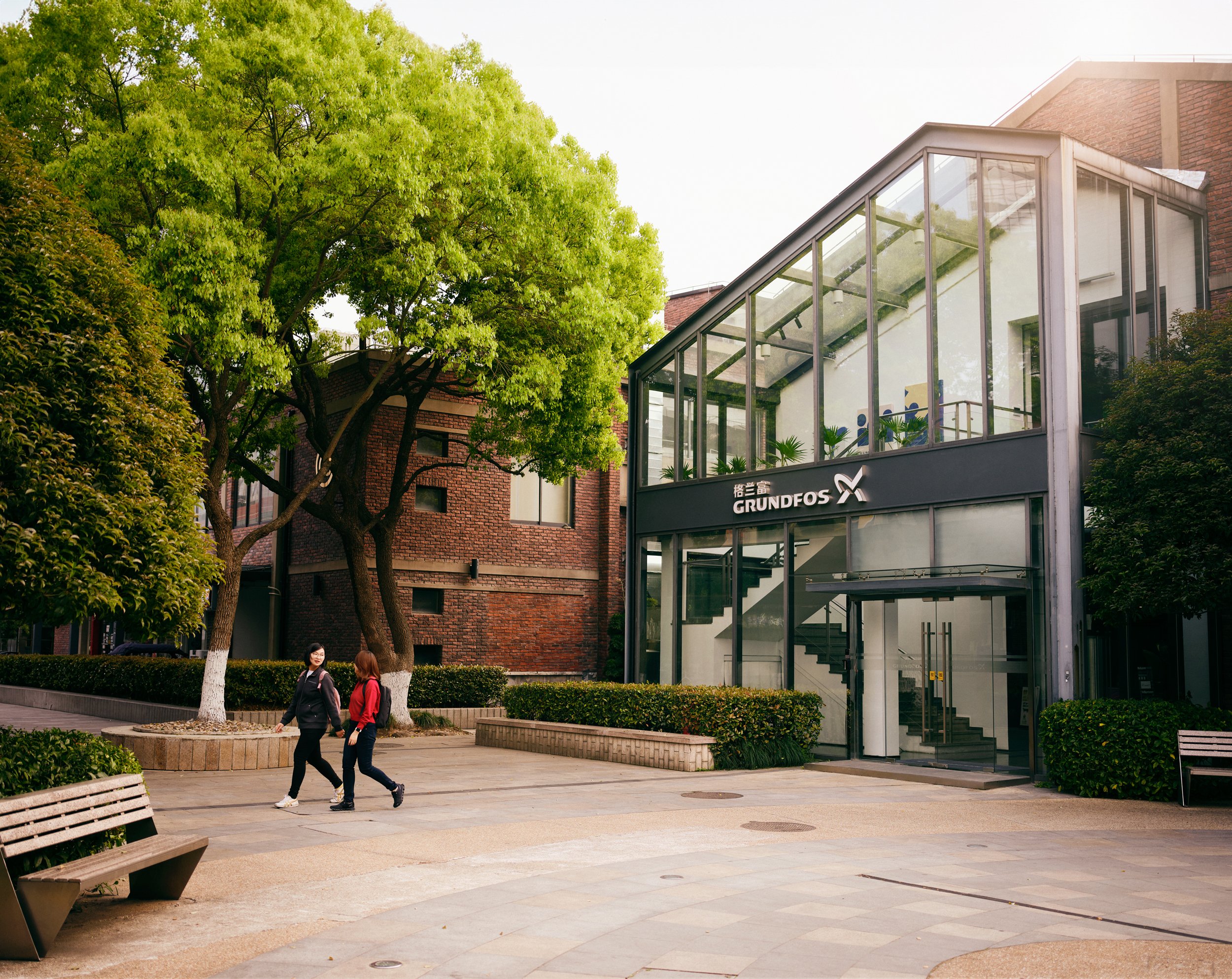 Grundfos office building in Shanghai exterior with employees walking through courtyard in daylight