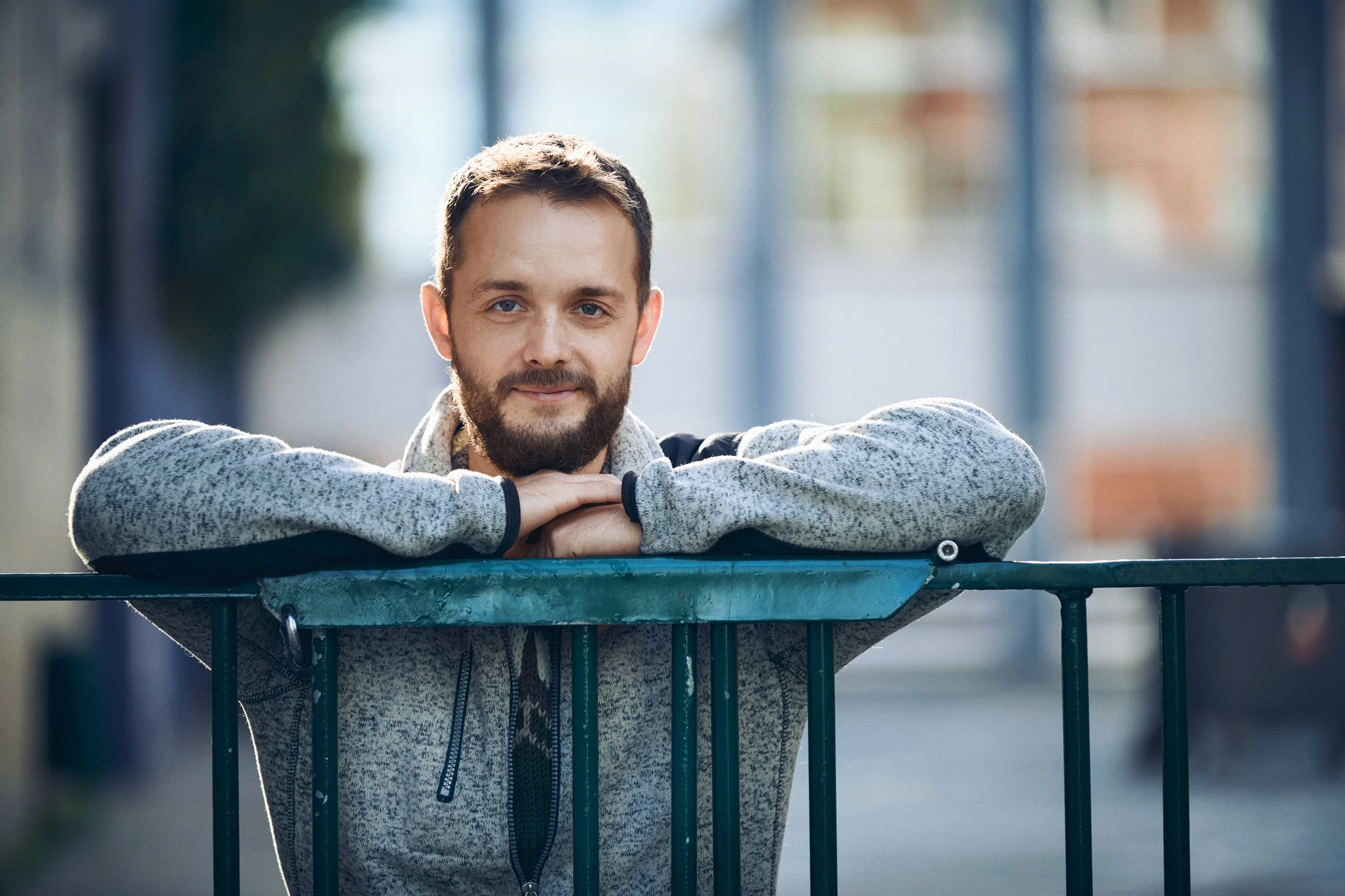 Portrait of man leaning on railing outdoors, calm expression in urban setting