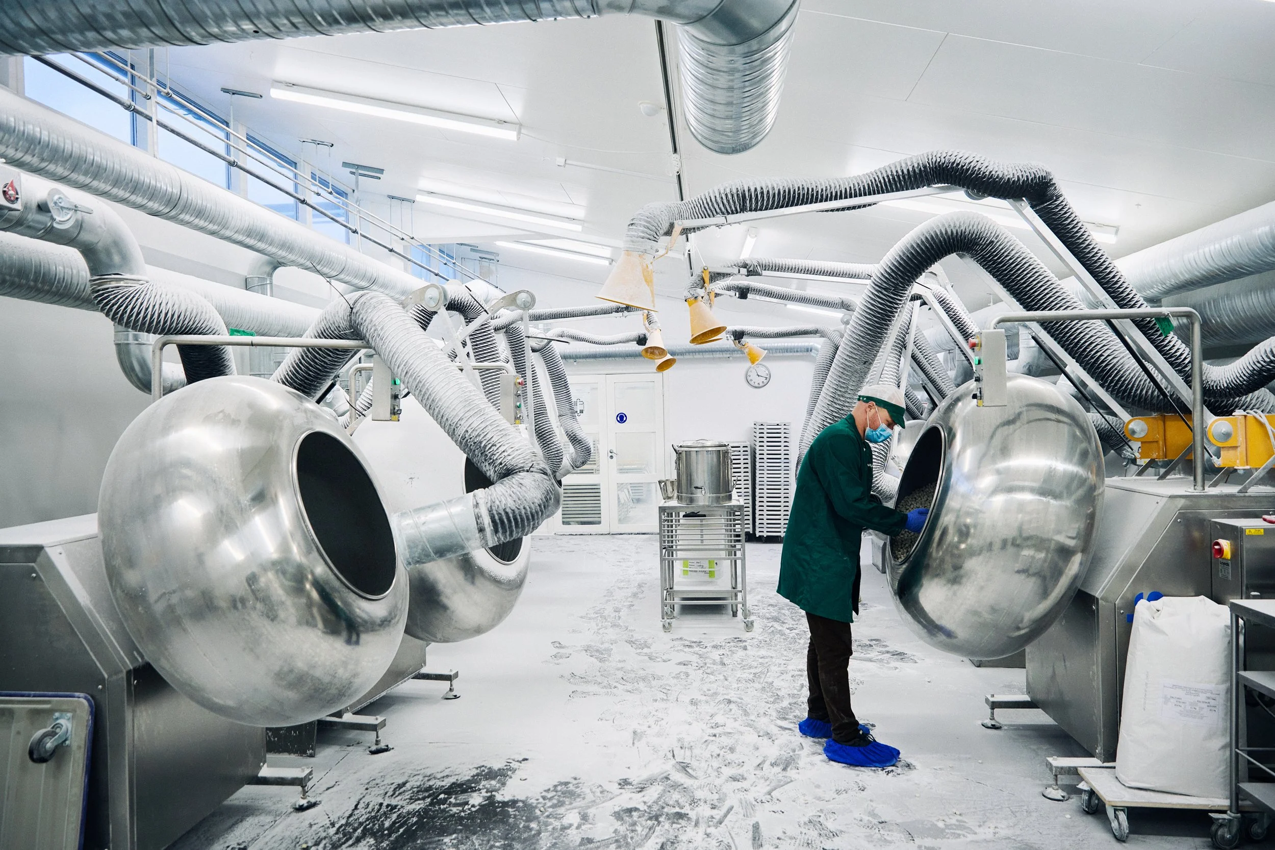 Technician standing among large industrial machines, production environment overview
