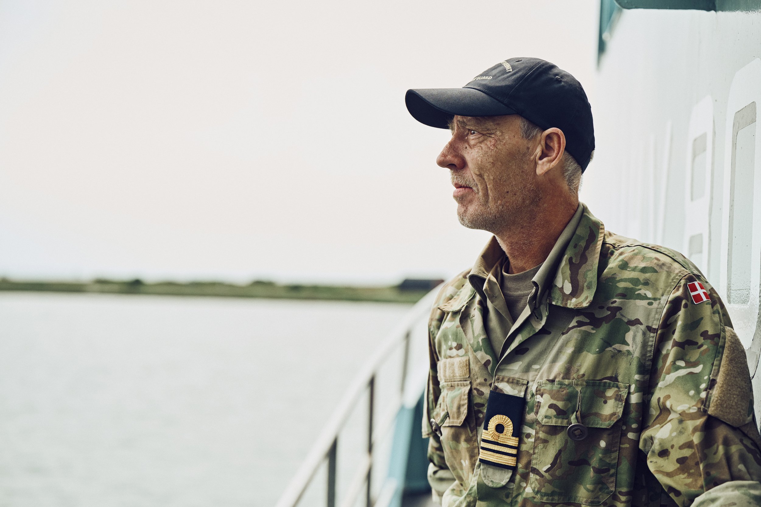 Home Guard soldier standing on ship deck looking out over water, side profile portrait
