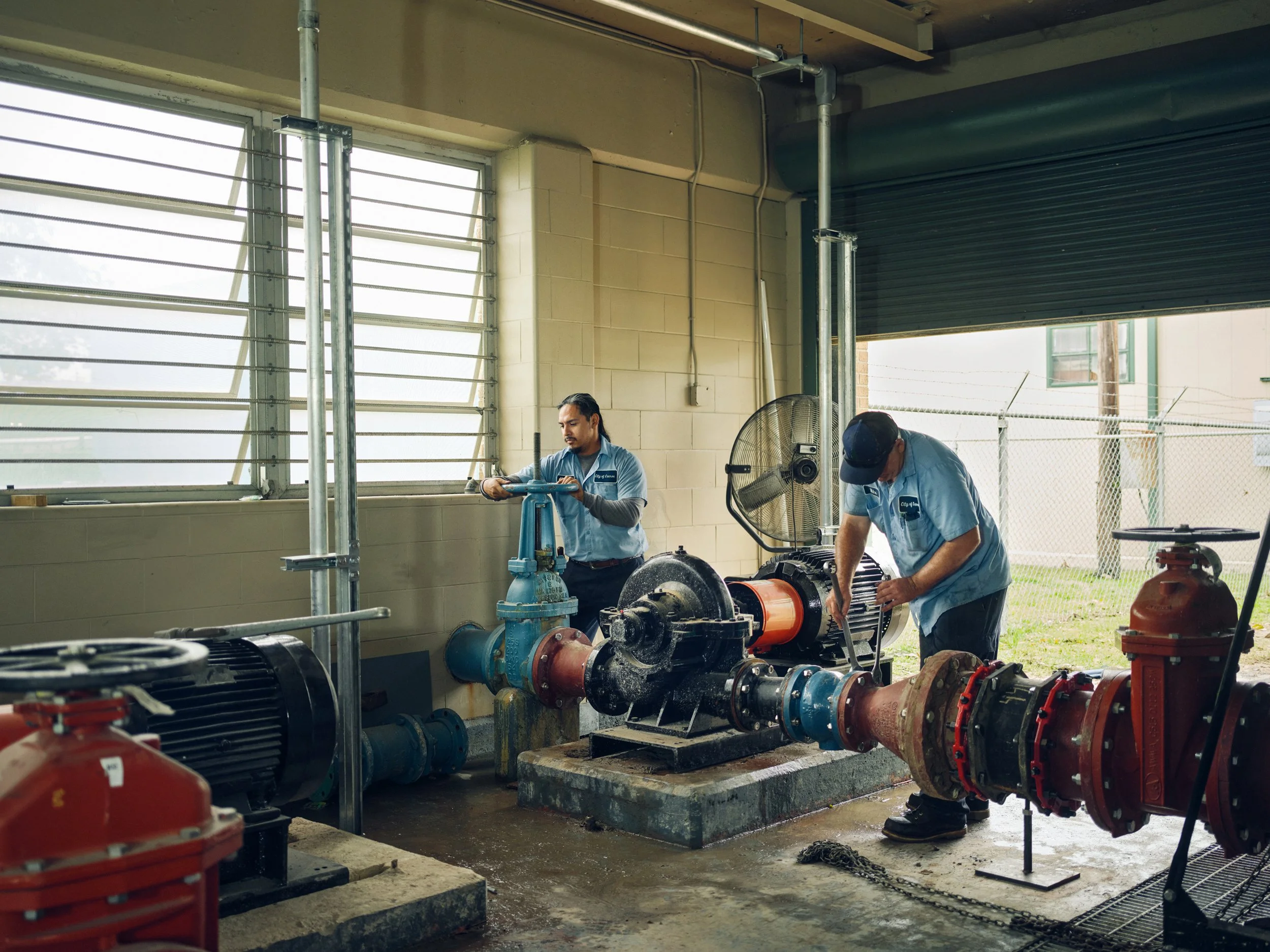Two technicians working on pump installation in mechanical room