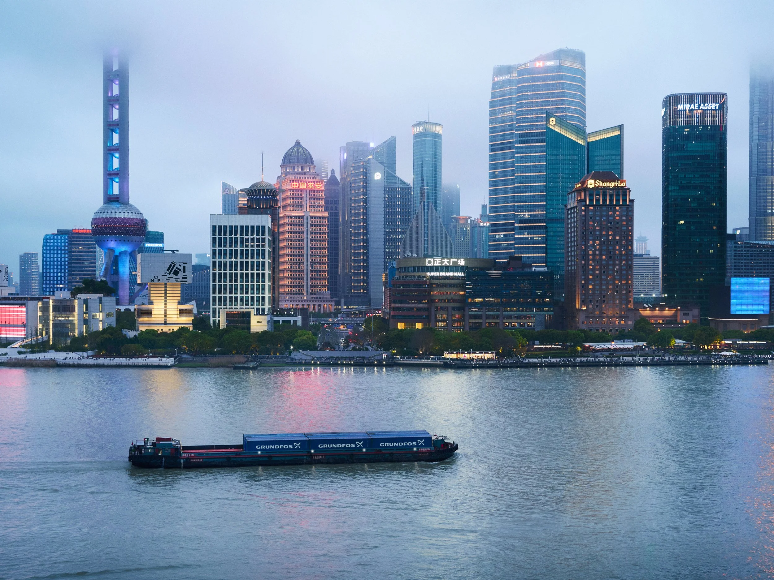 Cargo barge on river in front of Shanghai skyline
