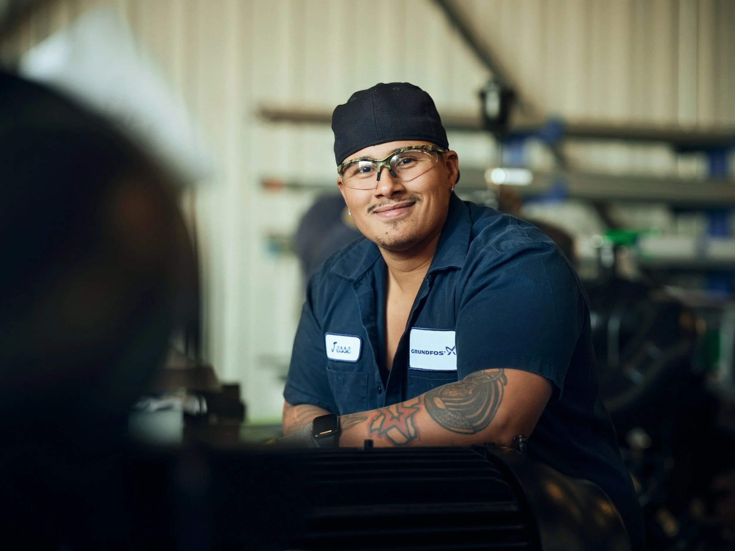 Portrait of technician in workshop environment, leaning on machinery and looking at camera