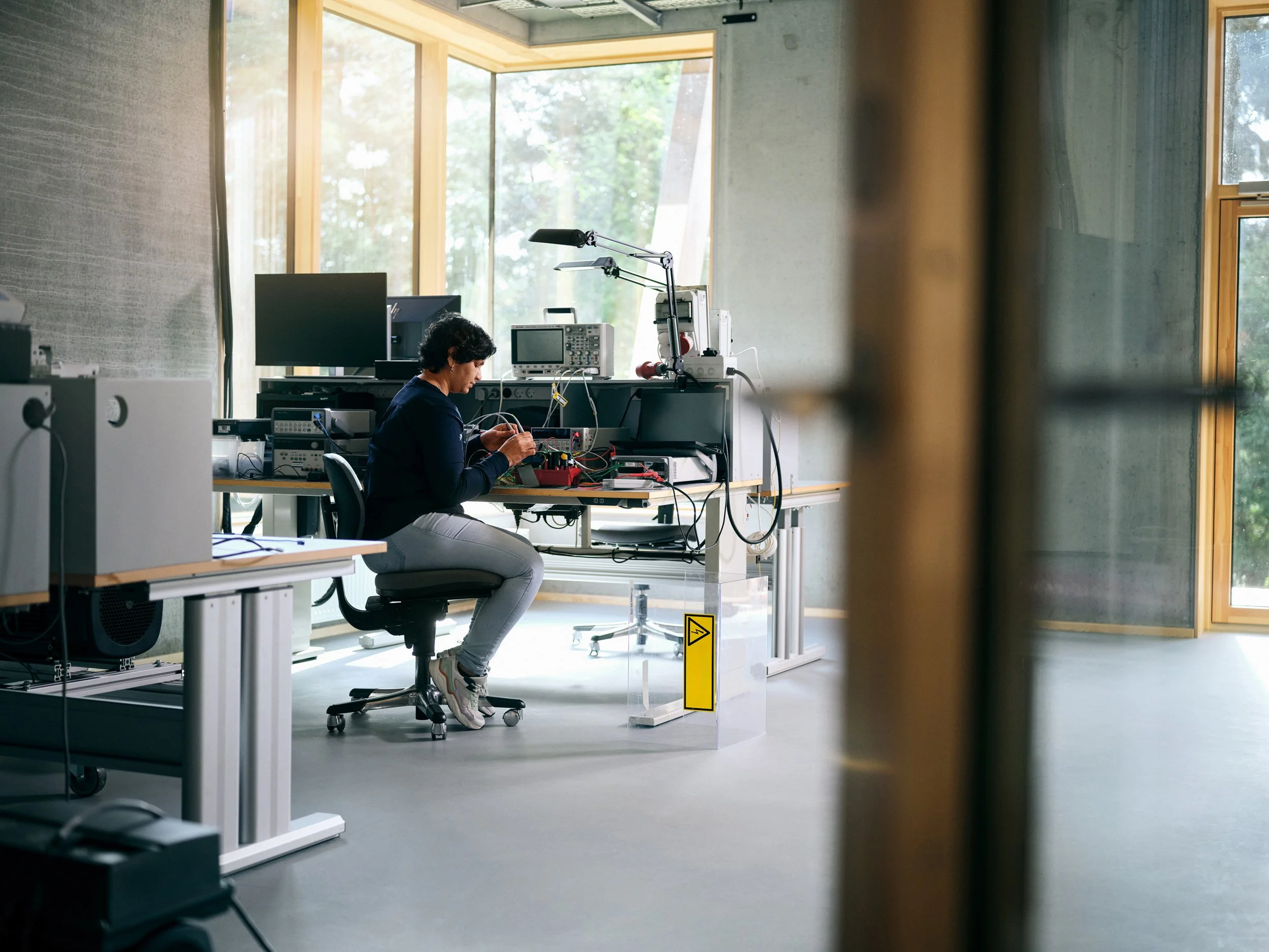 Engineer working at desk with electronic components and measurement equipment in R&D workspace