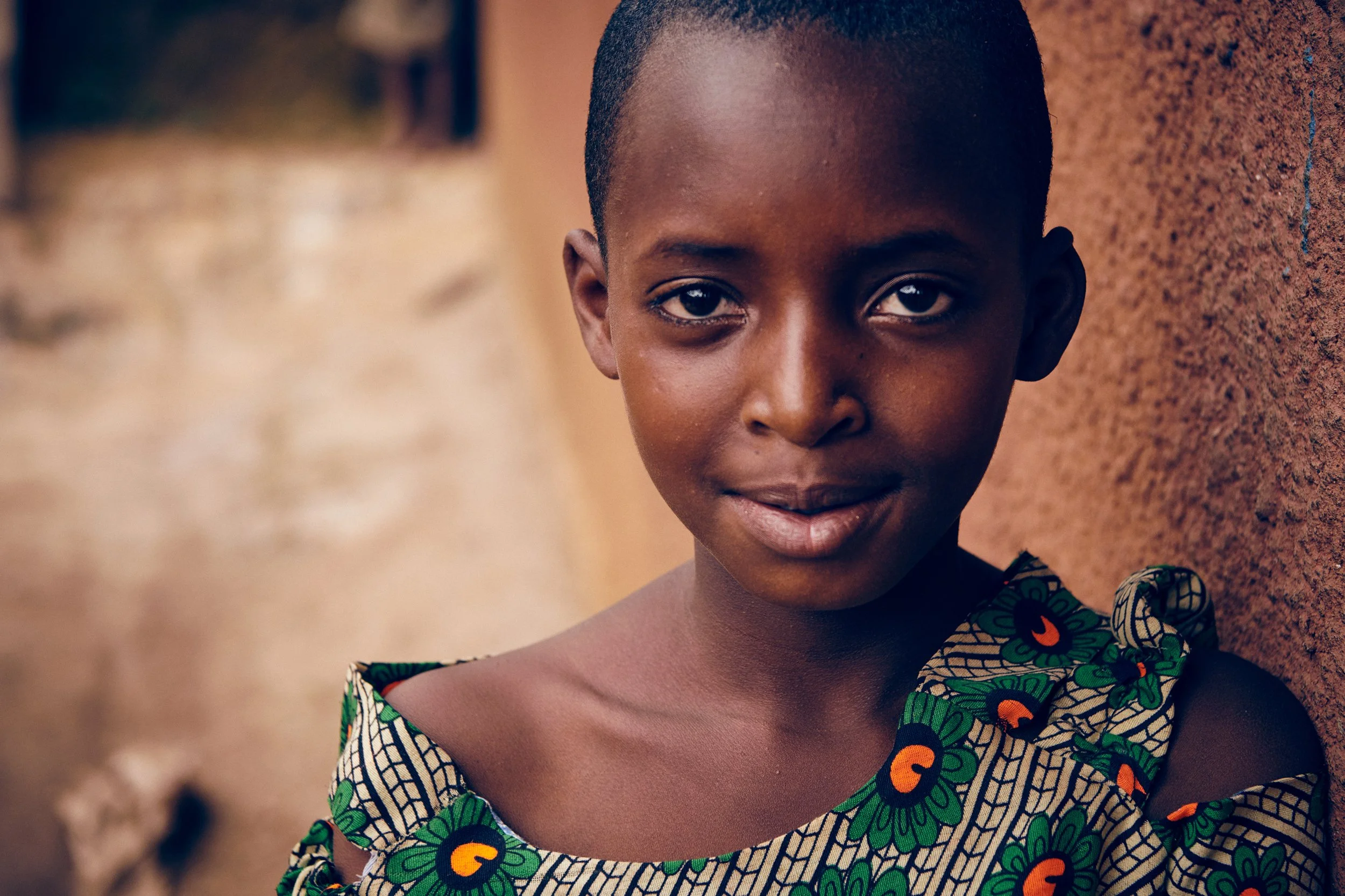 Portrait of young girl standing by wall, natural light and direct gaze