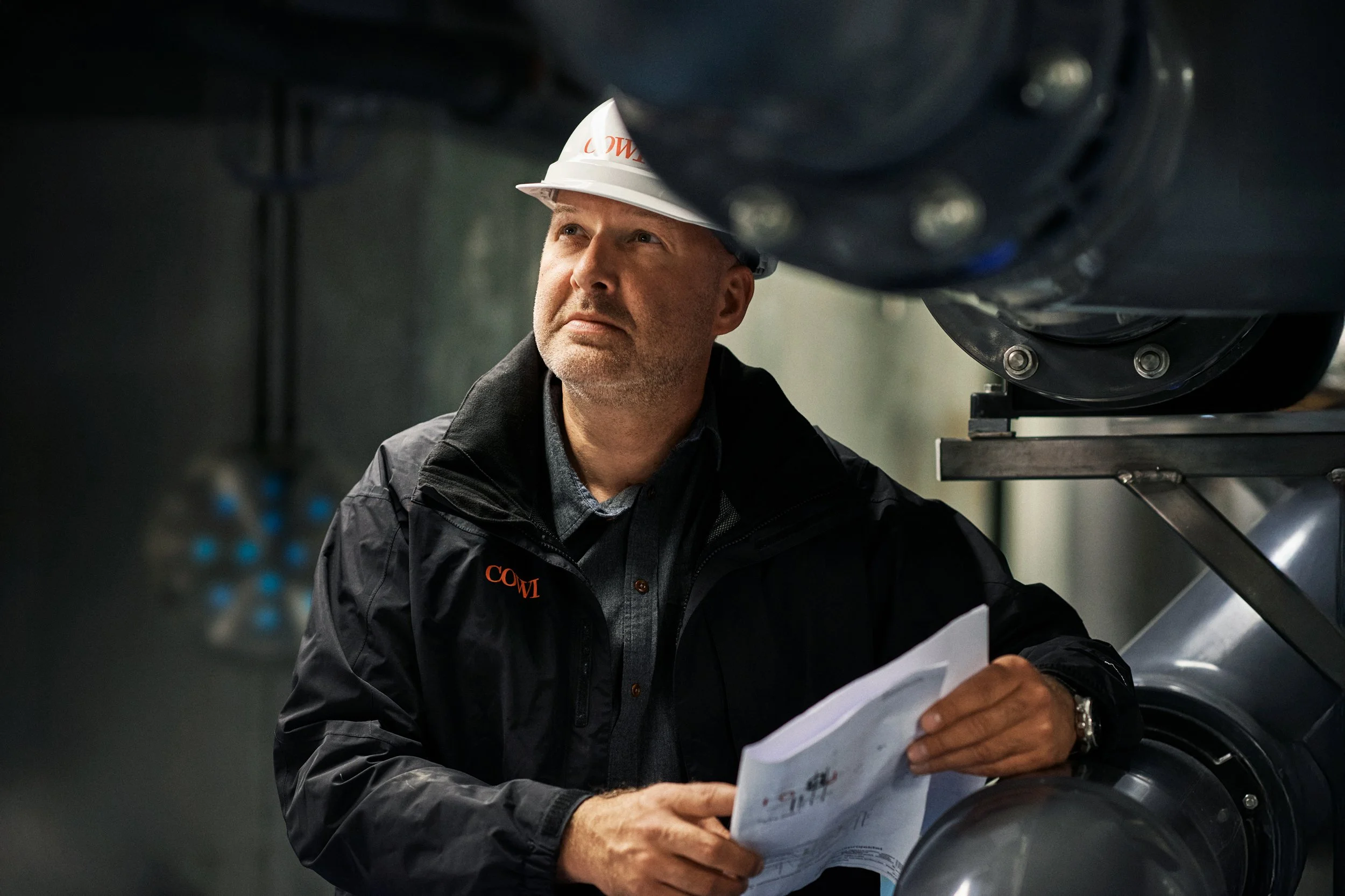 Engineer inspecting industrial installation holding drawings
