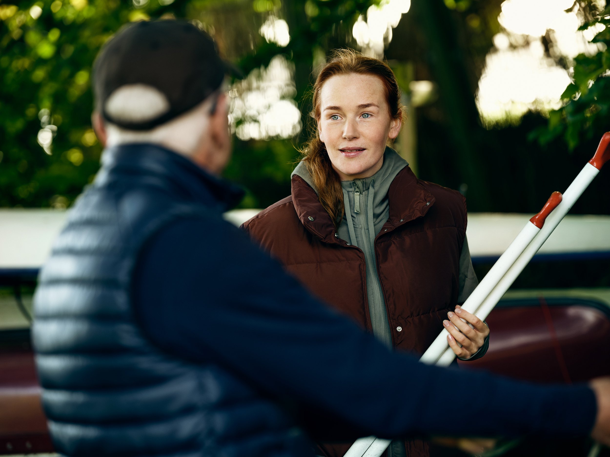 Two people handling boat equipment outdoors, preparing for activity near water
