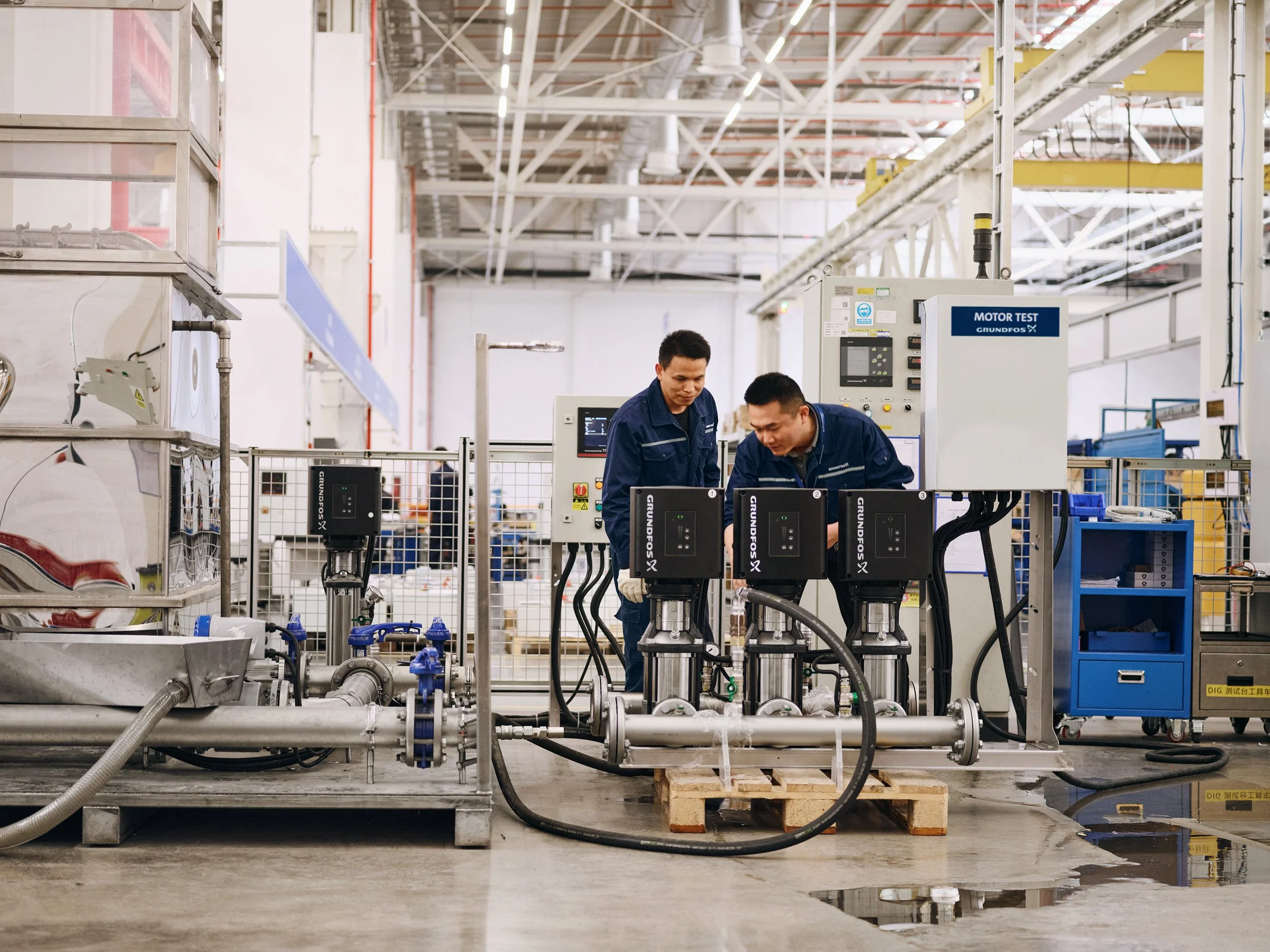 Technician operating motor test setup with visible piping and control systems