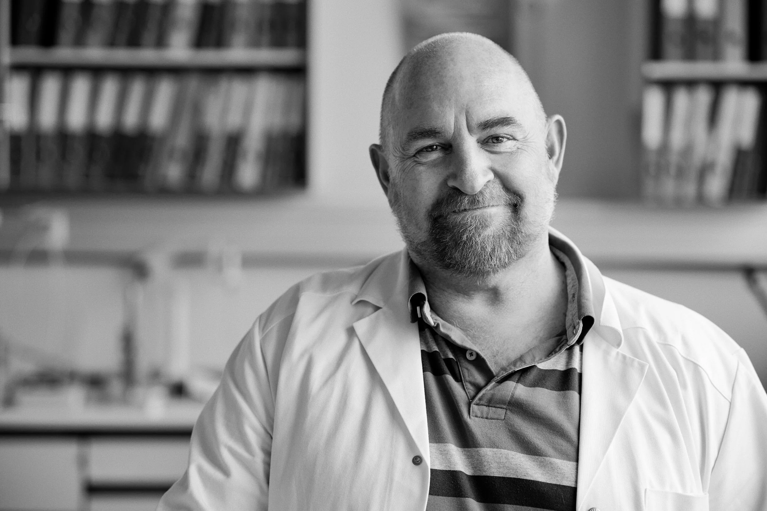 Portrait of researcher in laboratory environment, neutral background with technical context
