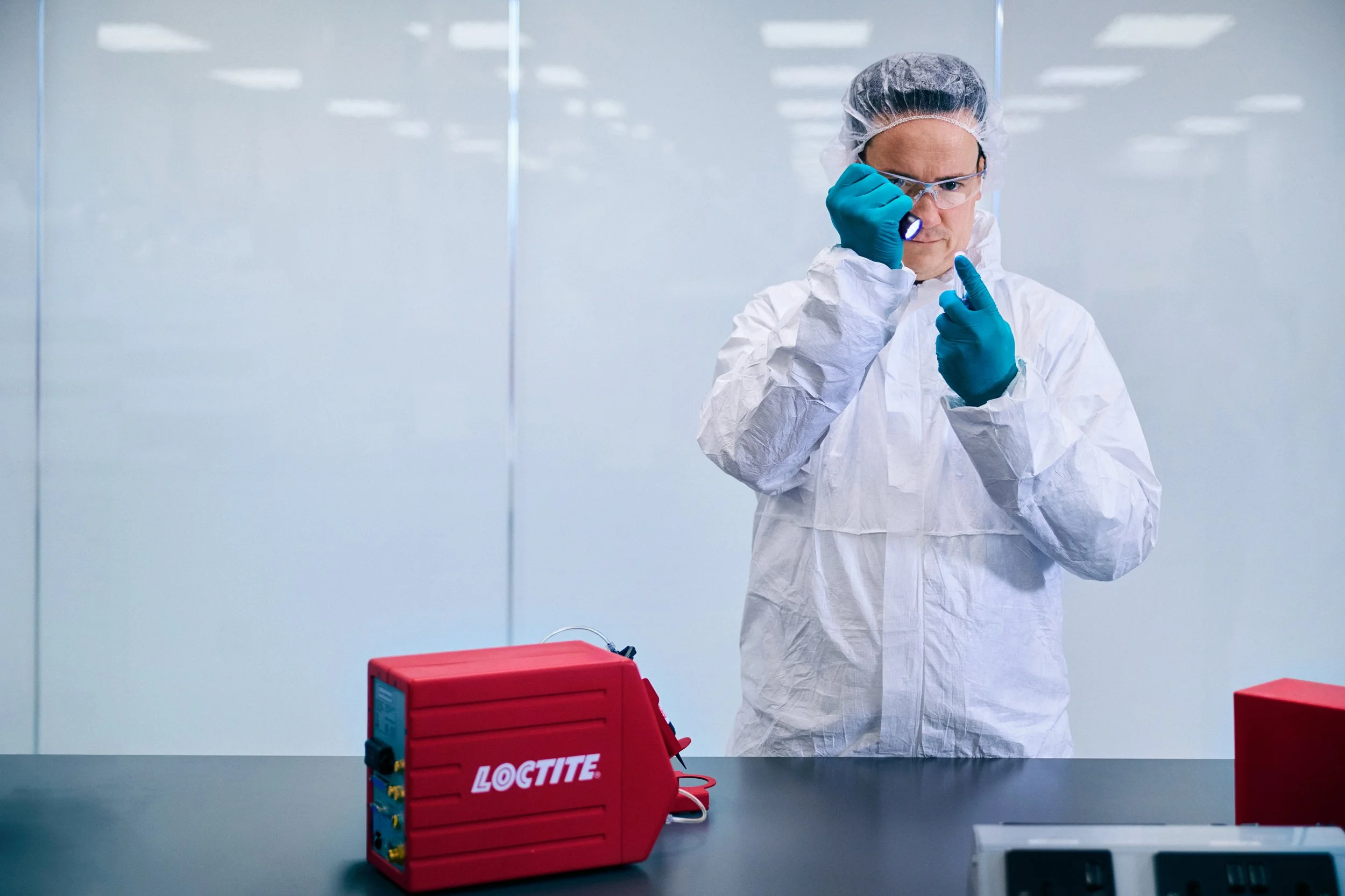 echnician in cleanroom inspecting small component with LOCTITE equipment on table
