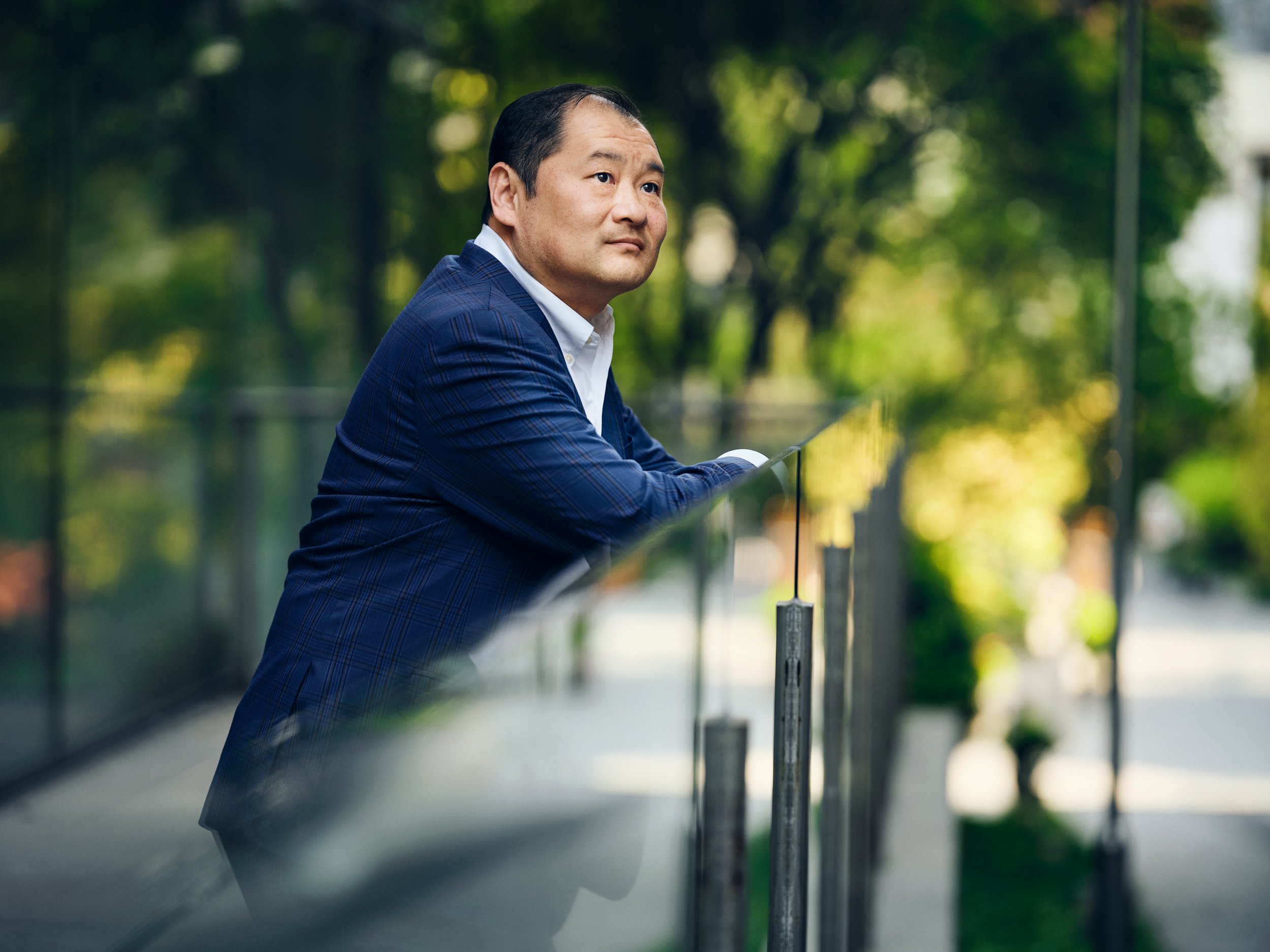 Business executive leaning on railing outdoors in corporate campus setting