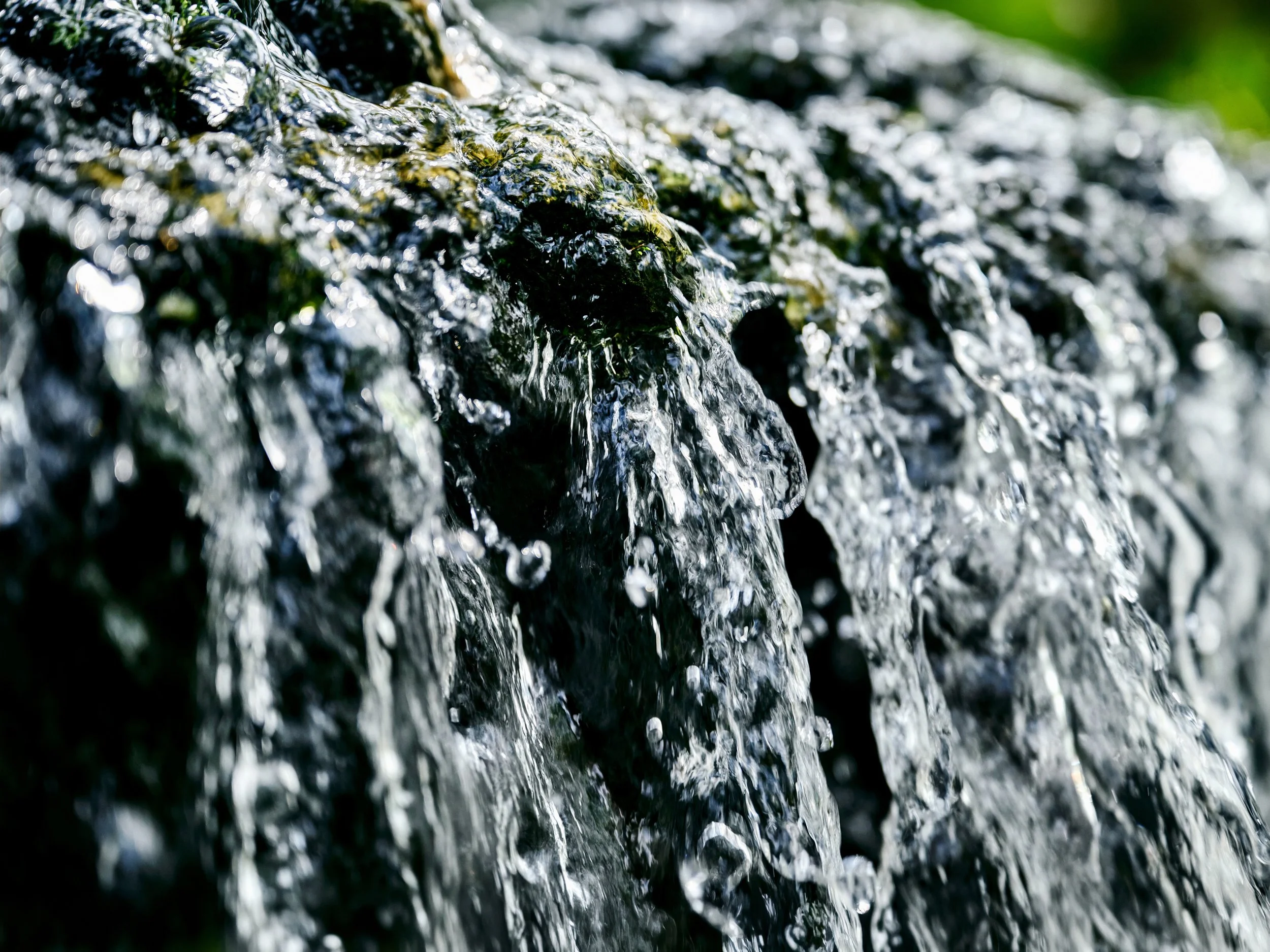 Close-up of water flowing over surface with droplets