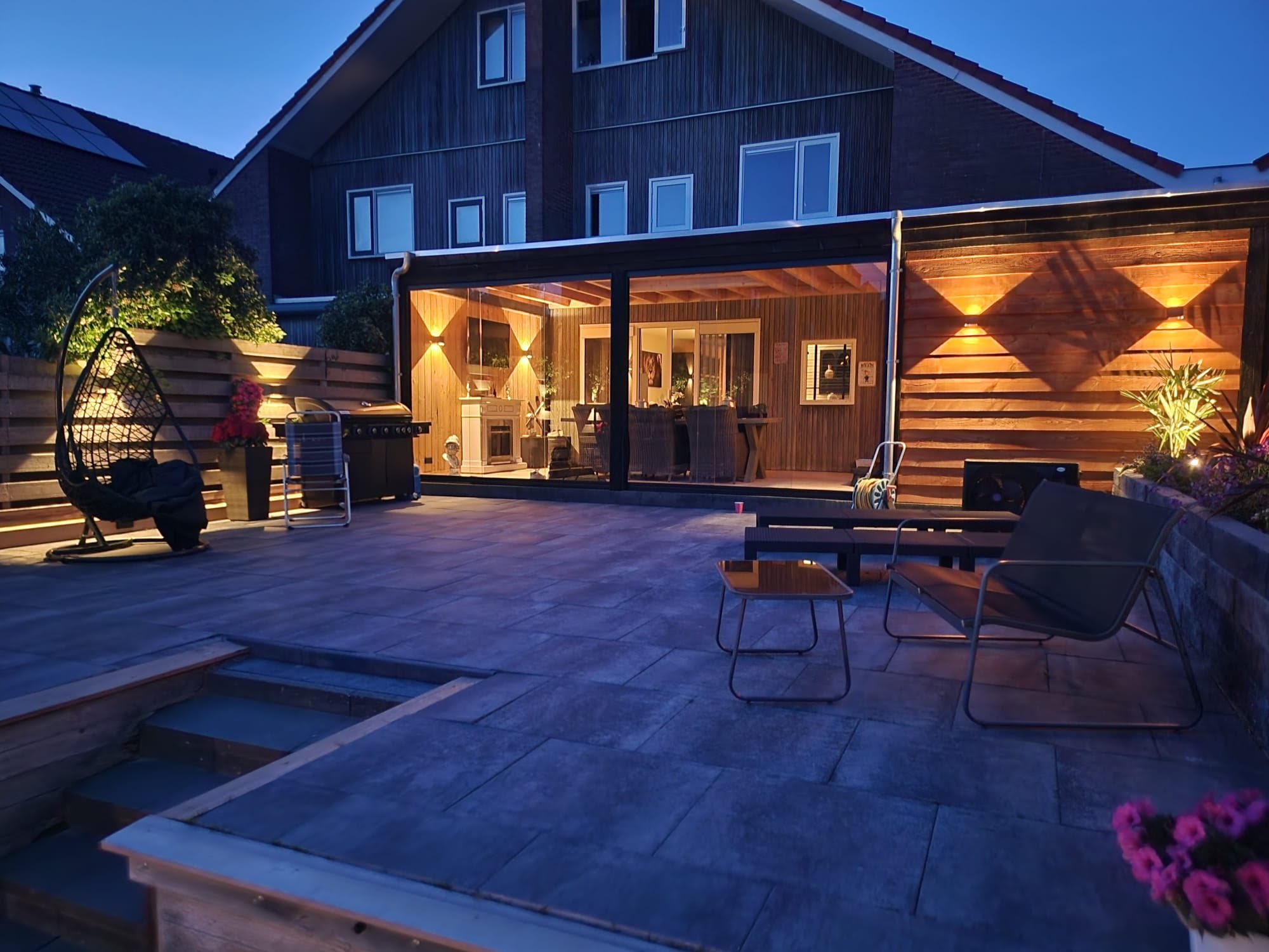 Een foto van een trap en een gerenoveerde tuin met sfeerverlichting