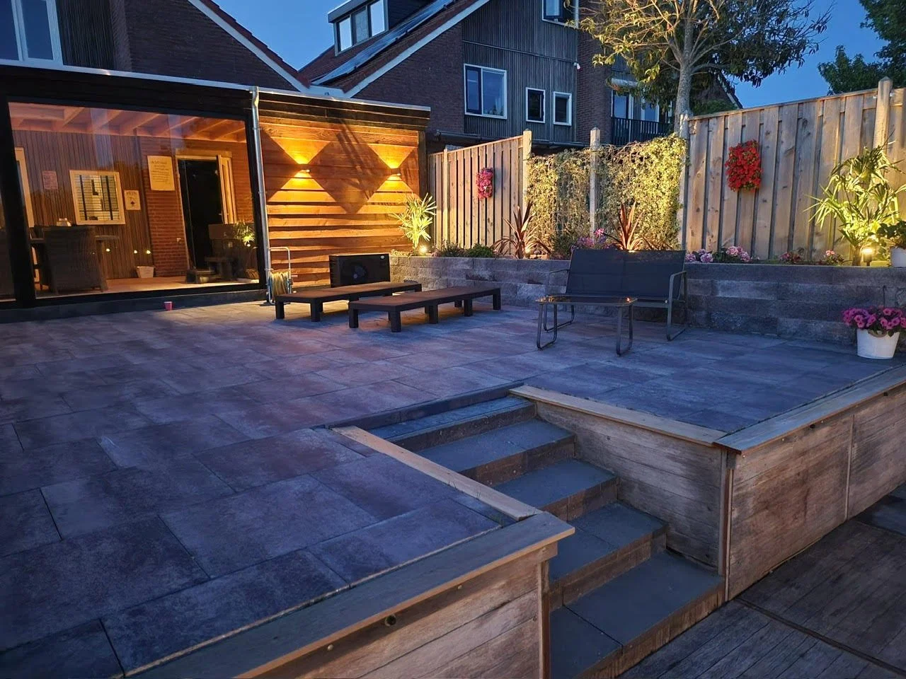 Een foto van een trap en een gerenoveerde tuin met sfeerverlichting