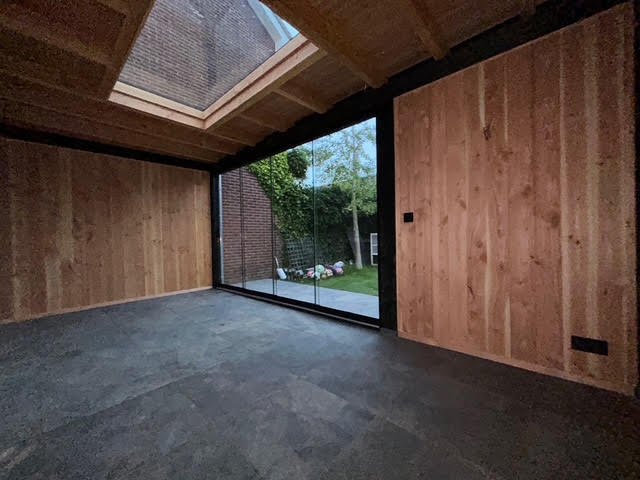 Een foto van een tuinhuisje met een glazen deur