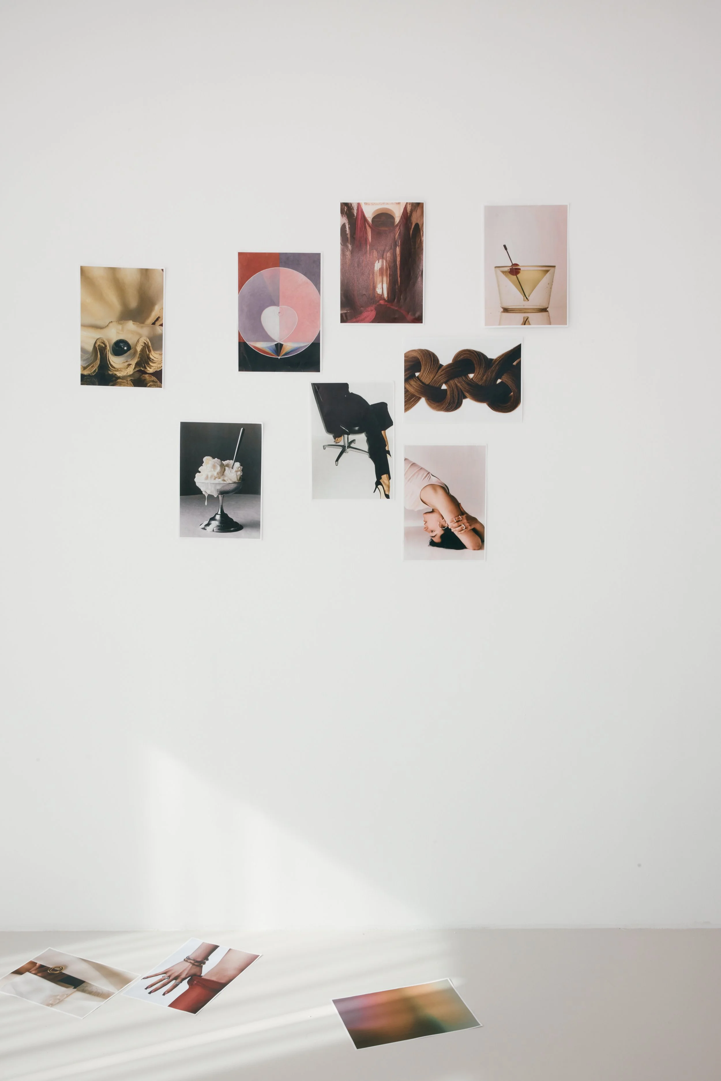 A white wall decorated with a collage of nine art prints arranged in a creative pattern.