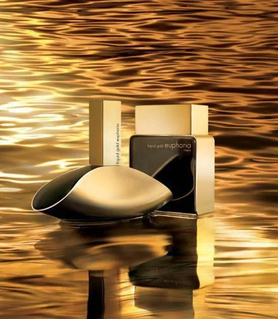 Beauty products including perfume and a device on a reflective water surface during sunset.