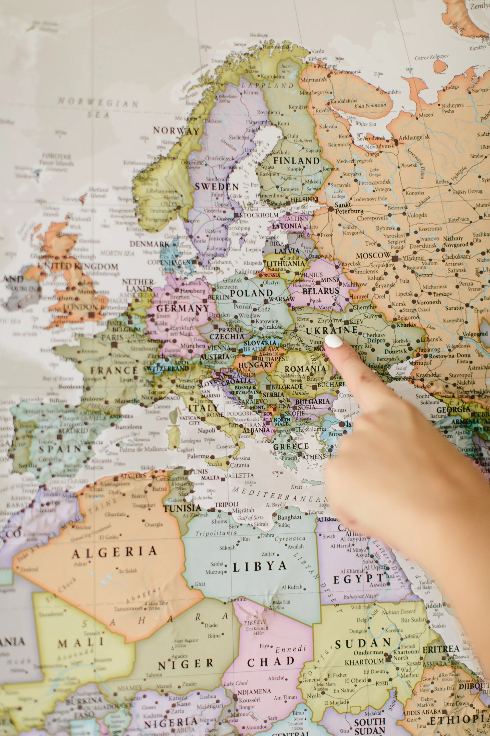 Person pointing on a detailed map of Europe and surrounding regions.