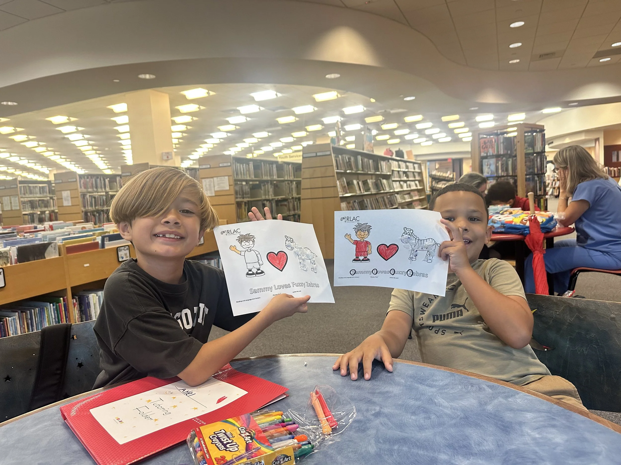 two children displaying their art work during a tutoring session at madelaines duluc learning