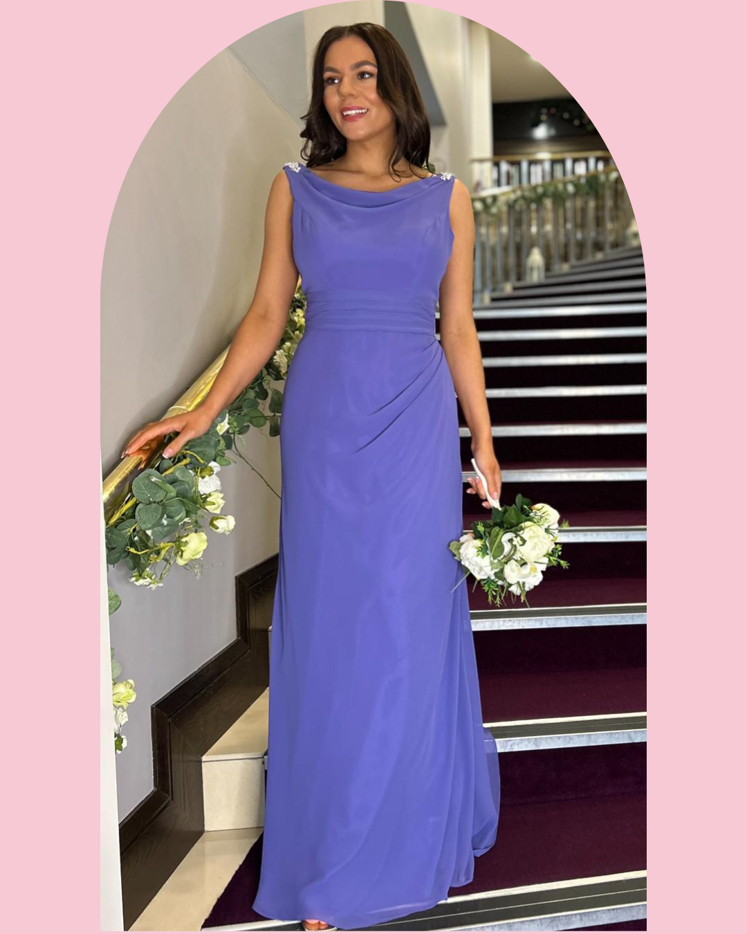 A woman in a purple evening gown holding a white flower bouquet standing on a staircase.