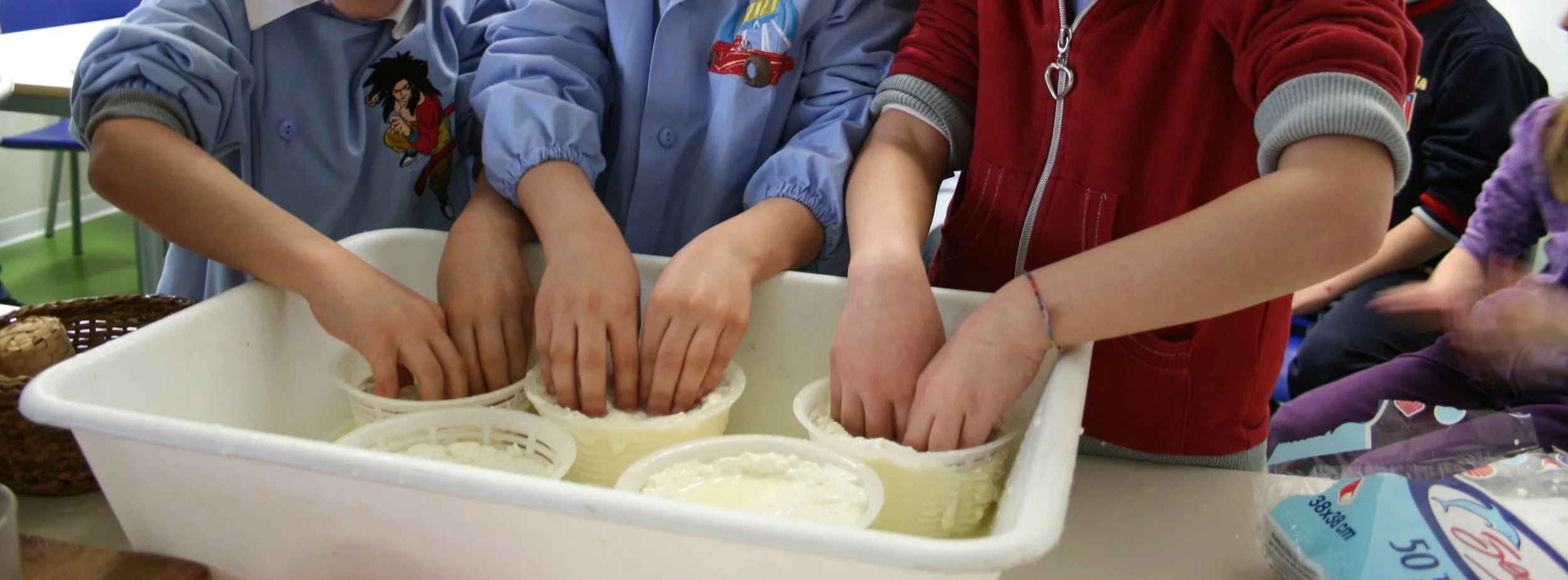 Children with hands dipped in ice cream in a classroom.