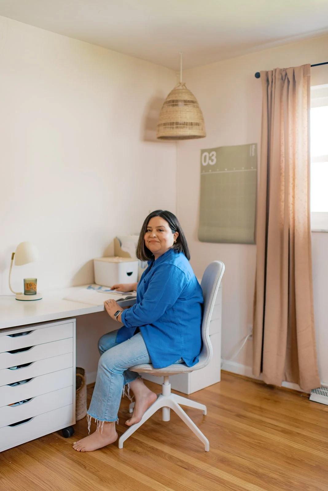 Woman sitting at desk smiling in blue shirt