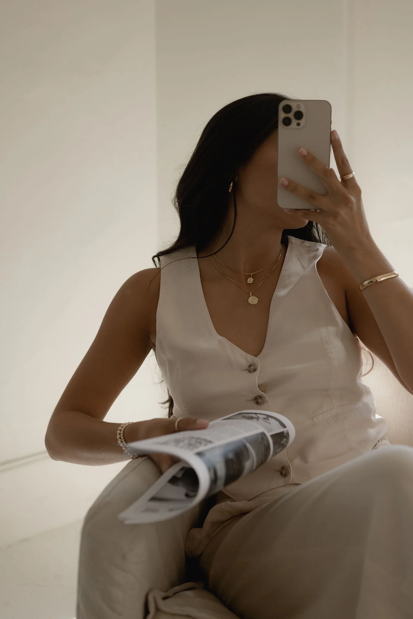 Woman in white vest suit taking selfie photo while sitting on chair