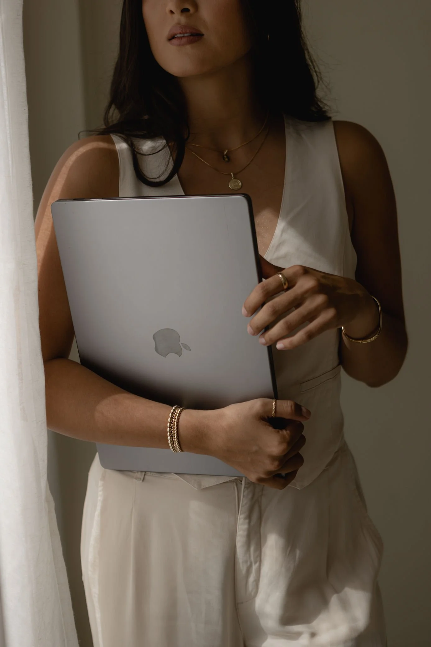 Woman holding her laptop next to a window