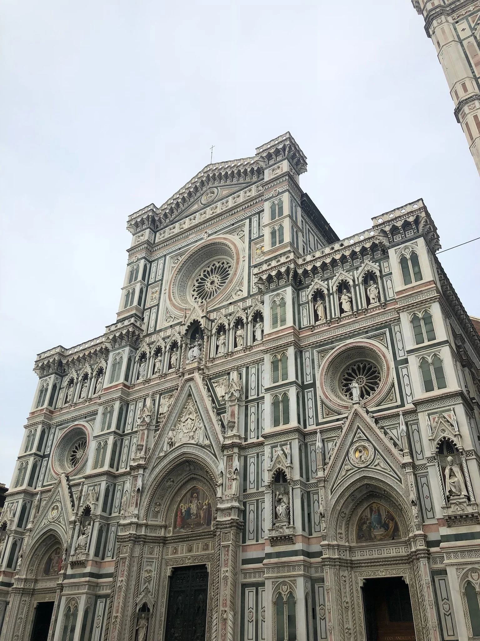 Exterior view of the Florence Cathedral (Cattedrale di Santa Maria del Fiore) with detailed marble facade and gothic architecture in Florence, Italy.