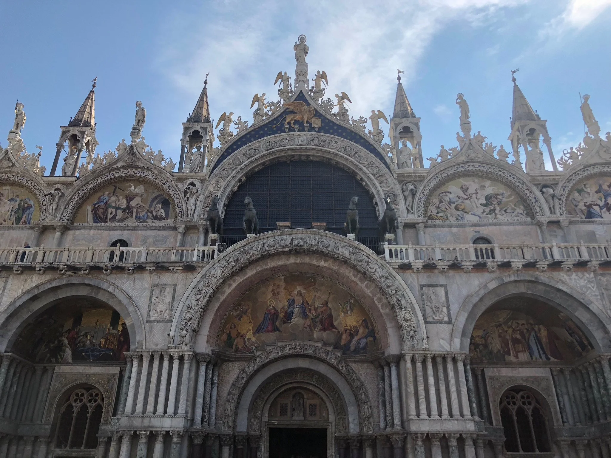 The facade of St. Mark's Basilica in Venice, Italy, featuring ornate architecture, statues, and mosaics.