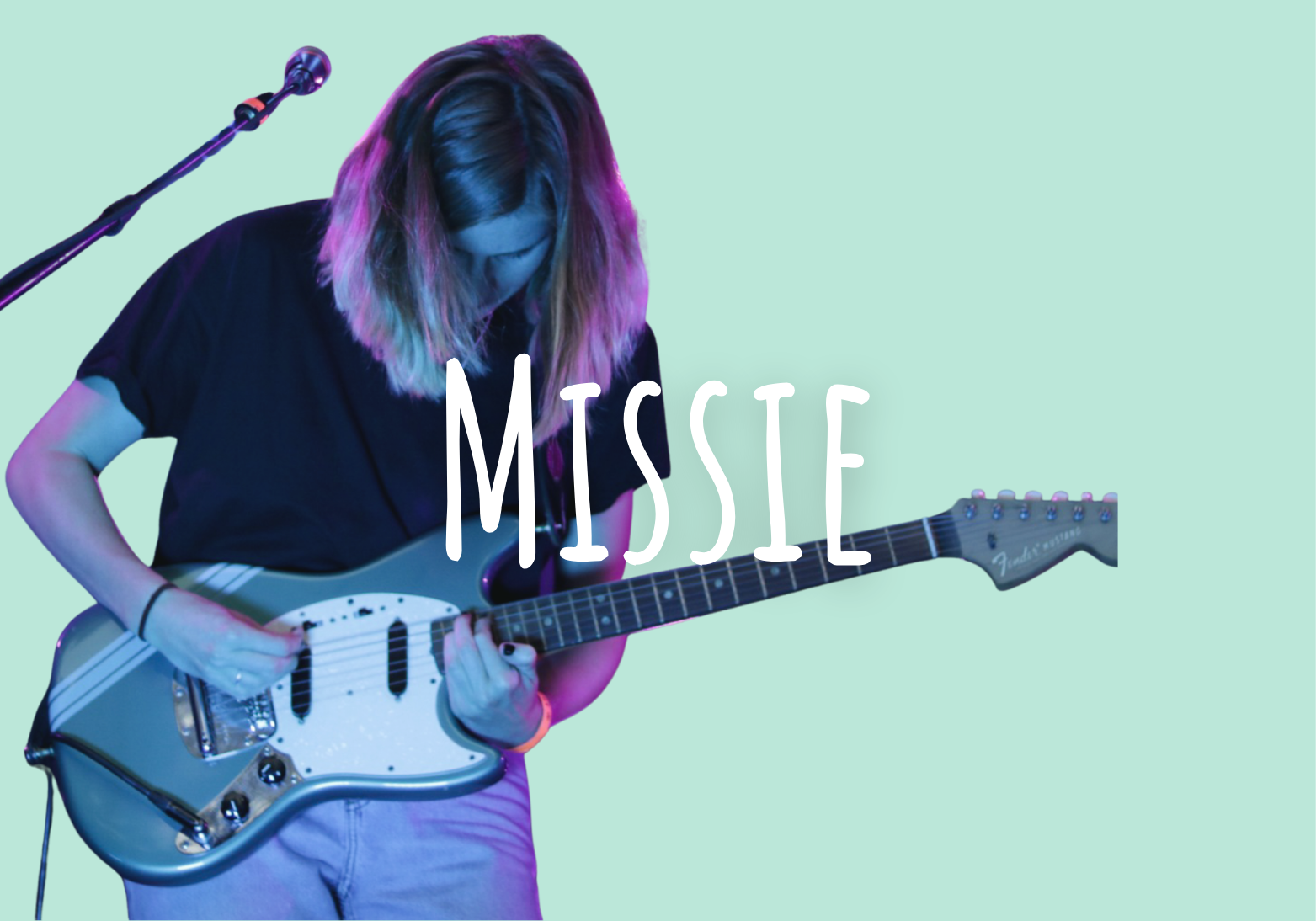 A person with long hair playing an electric guitar on stage, with the word 'MISSIE' overlaid.