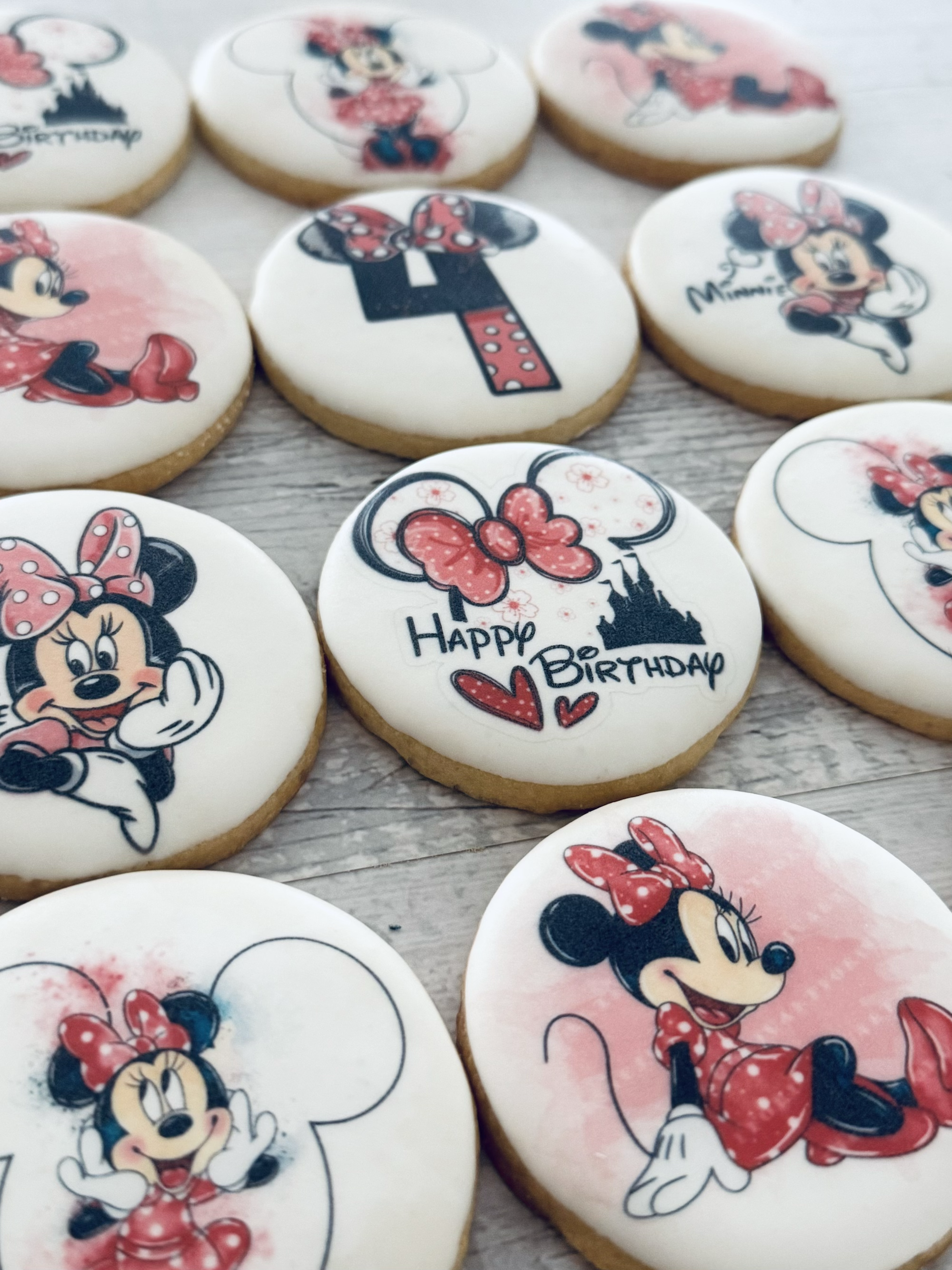 Decorated cookies featuring Minnie Mouse and birthday-themed designs on a wooden surface.