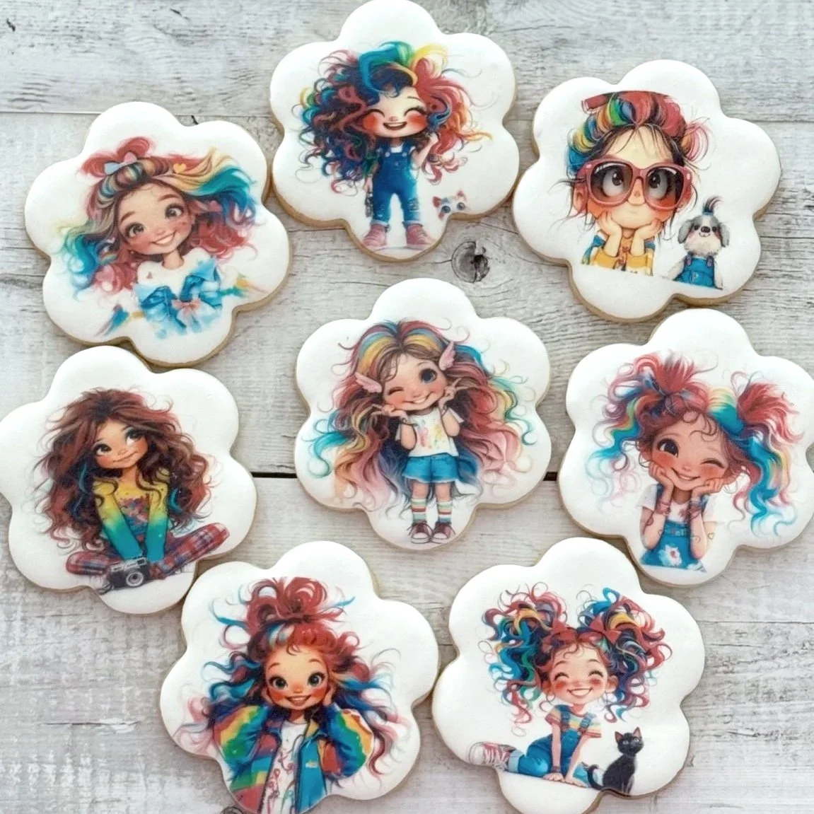 A set of cookies decorated with colorful, cartoon-style illustrations of a young girl with multicolored, curly hair and various playful poses.