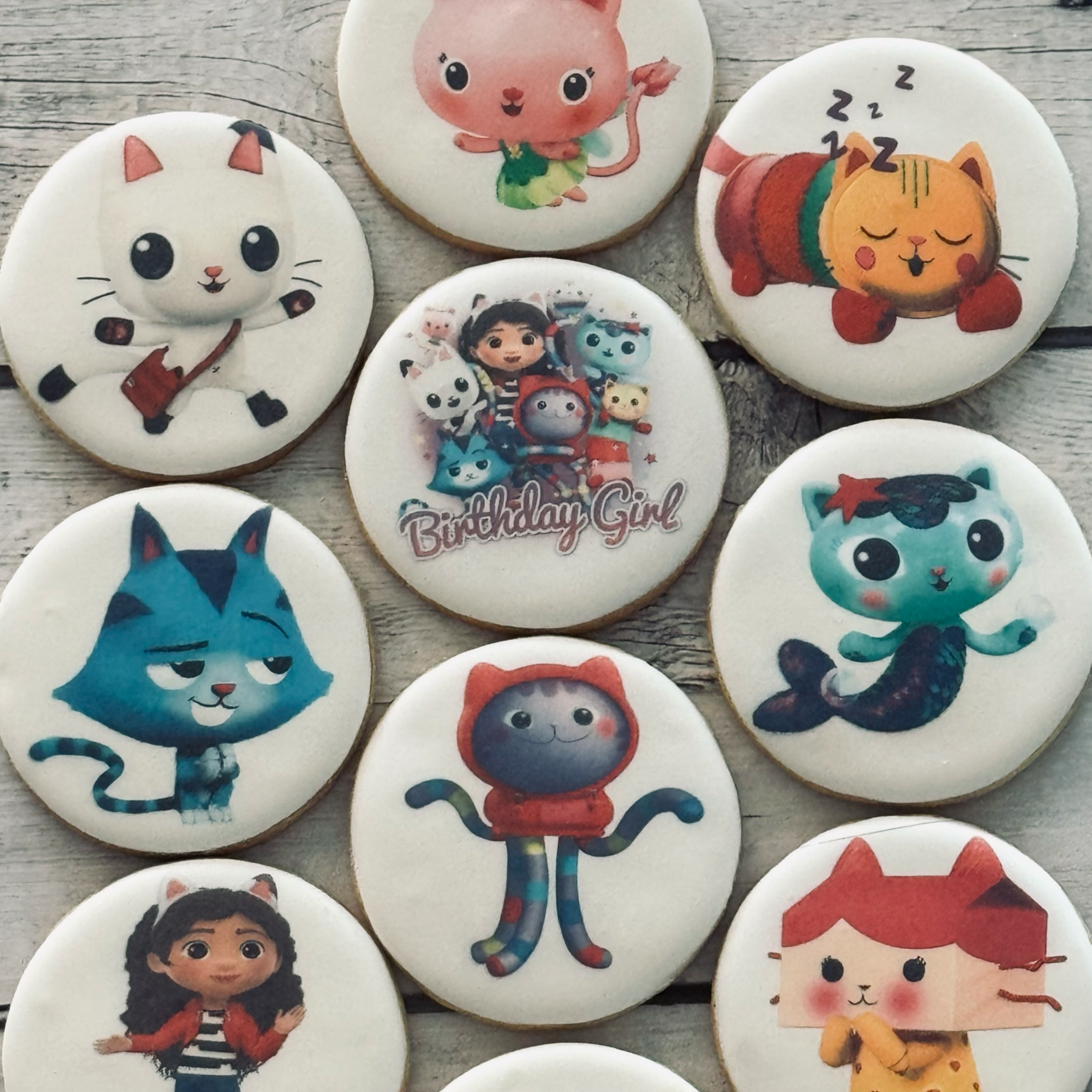Decorative cookies with cartoon characters including cats, a girl, a mermaid, and a girl with pigtails, some with birthday themes.