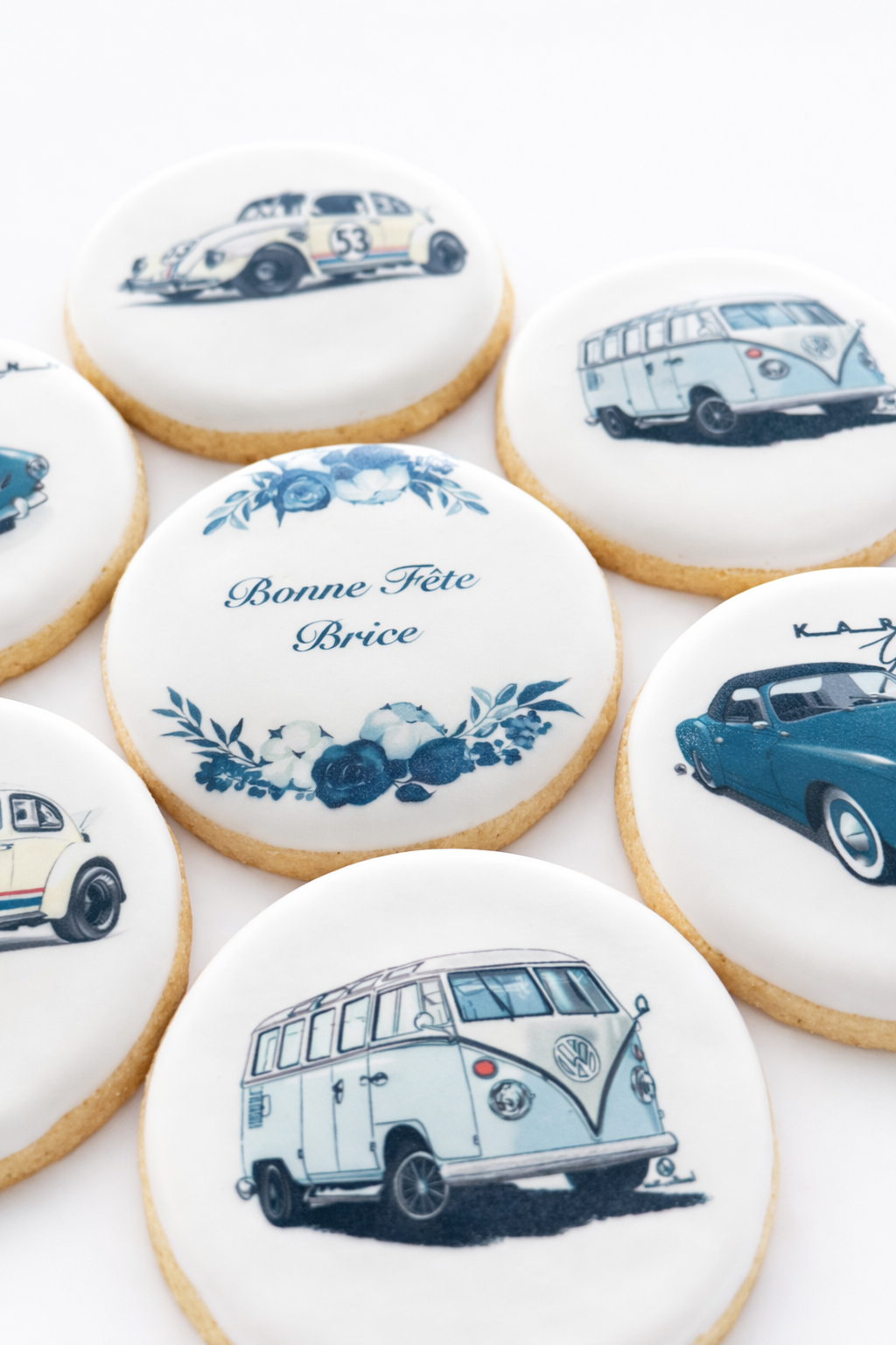 Cookies decorated with images of vintage cars, including a Porsche 911, a Volkswagen Type 2, and a classic Mini, along with a cookie with French text 'Bonne Fête Brice' and floral illustrations.