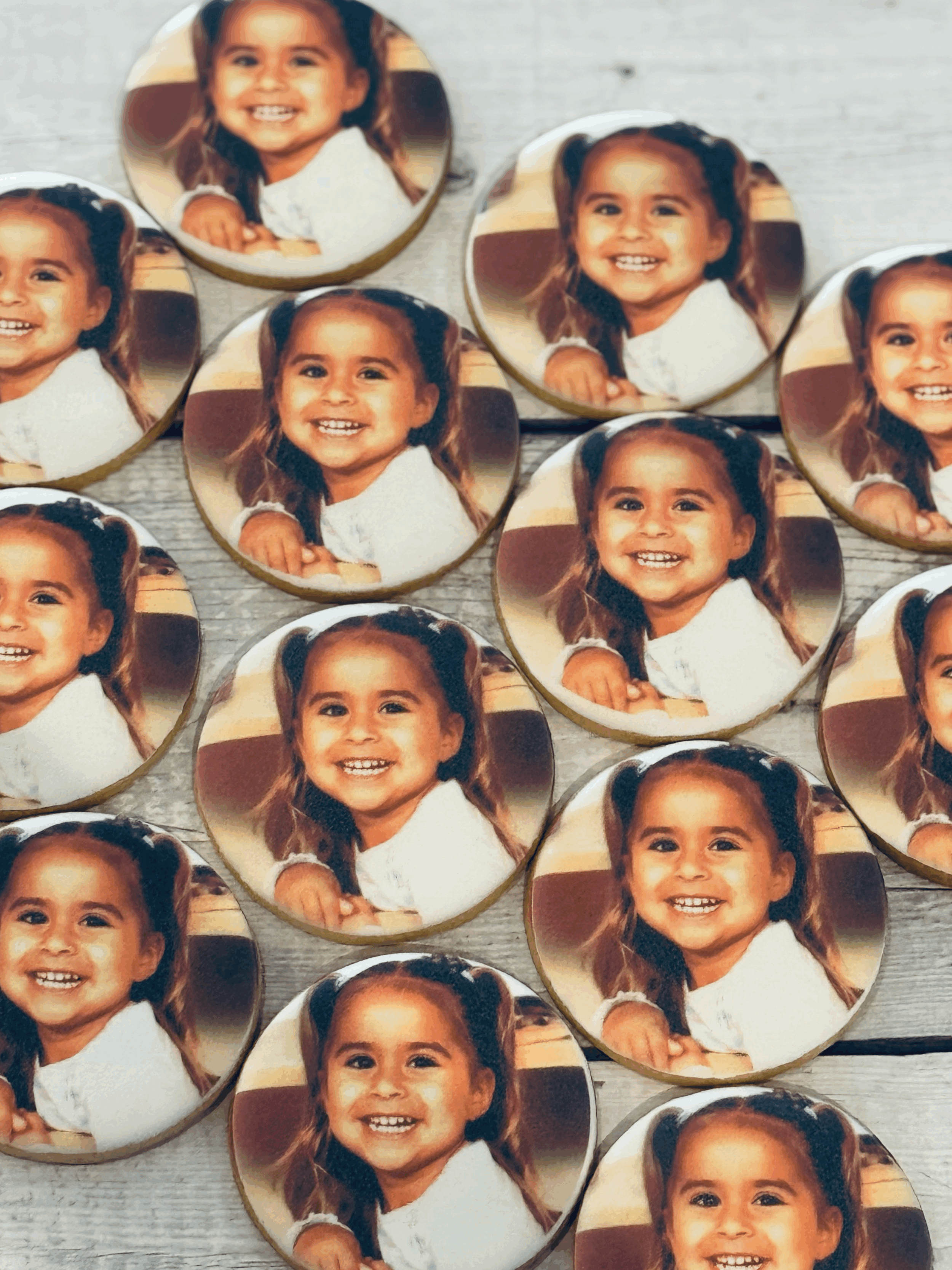 Collection of circular photo magnets with a smiling young girl with brown hair in pigtails, wearing a white shirt, on a light-colored surface.