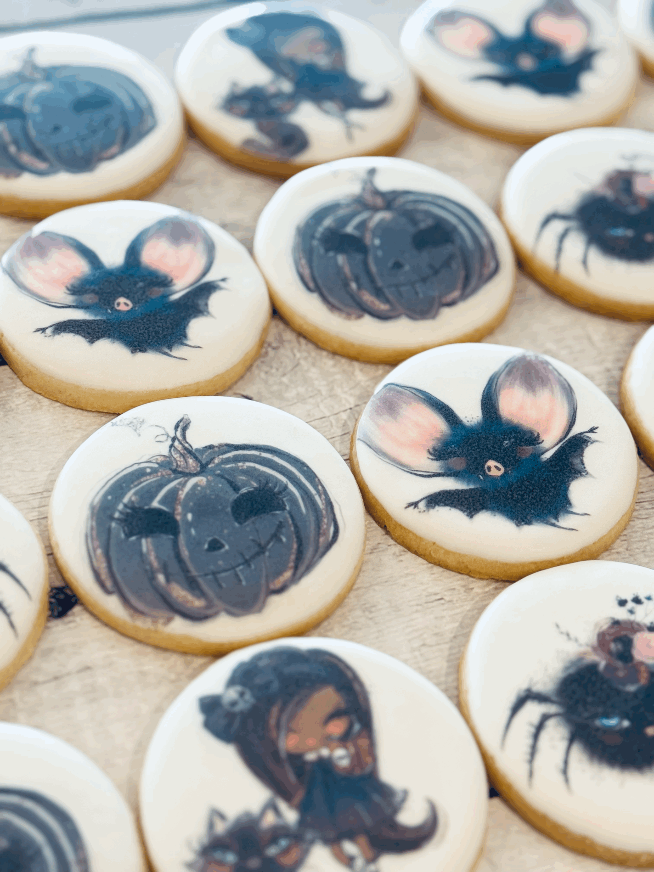 Halloween-themed decorated cookies with images of a bat, pumpkin, and witch.
