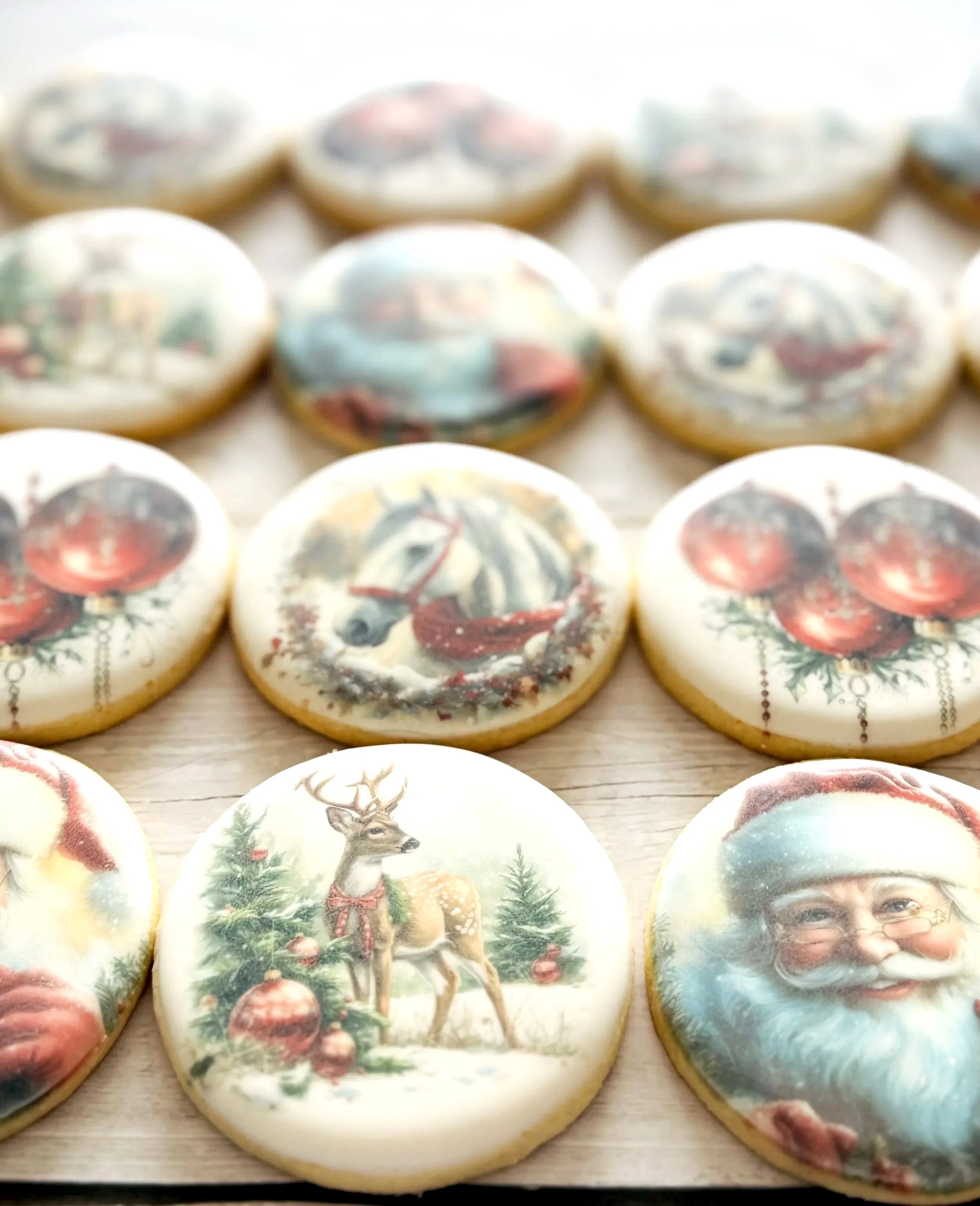 Decorative cookies with Christmas and winter holiday images, including Santa Claus, a reindeer, a horse with a wreath, and Christmas ornaments, arranged on a wooden surface.