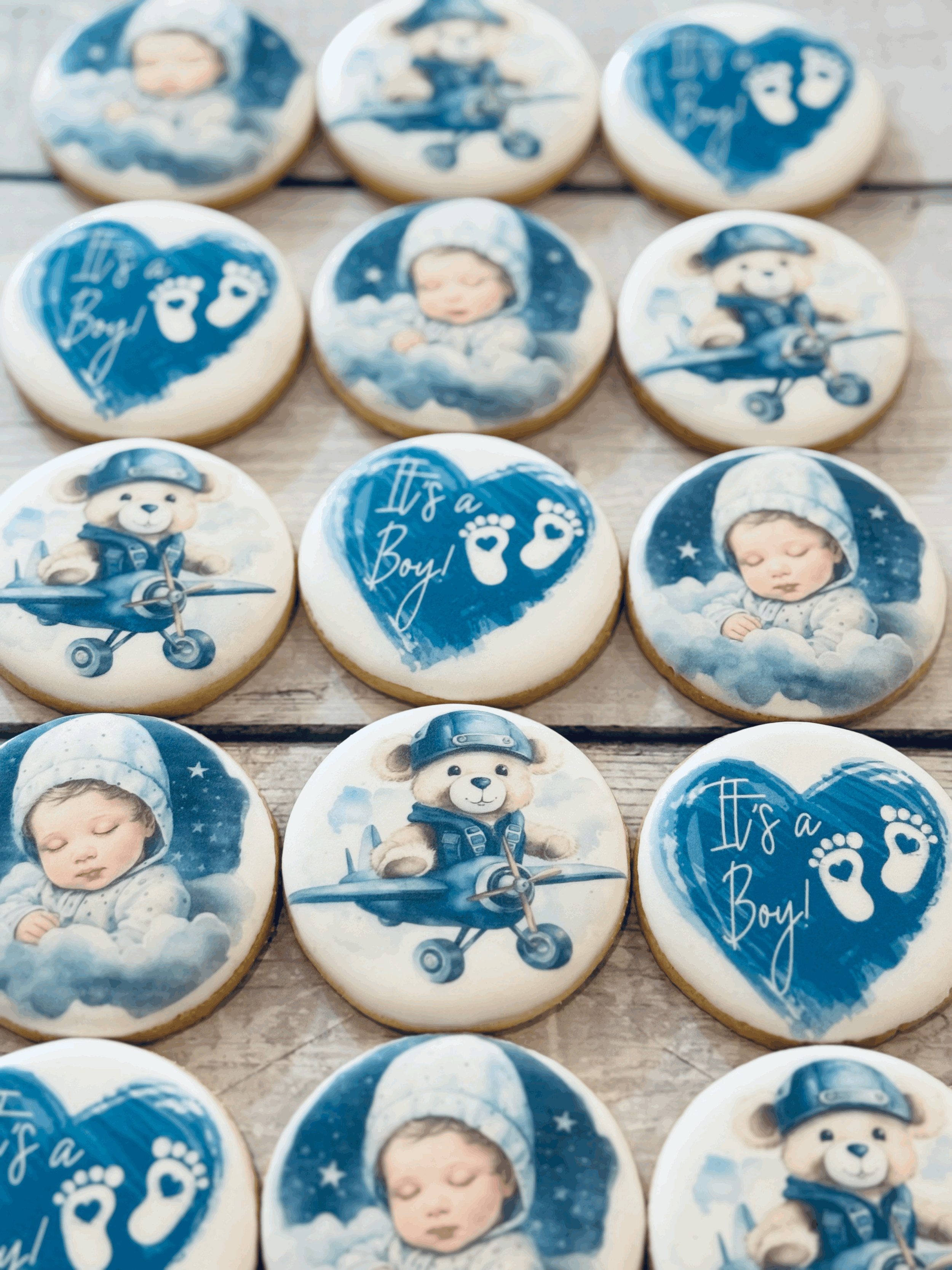 Decorative cookies with baby boy theme featuring a sleeping baby, teddy bears dressed as pilots, and a message 'It's a Boy!'