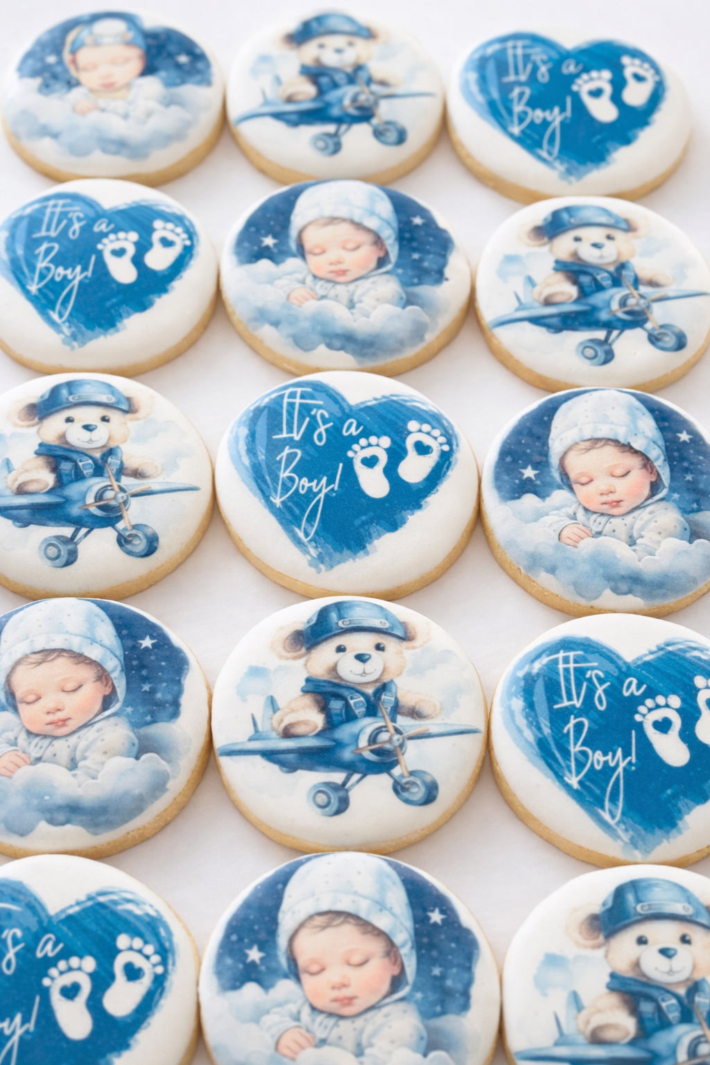 Decorative cookies with baby boy theme featuring a sleeping baby, teddy bears dressed as pilots, and a message 'It's a Boy!'