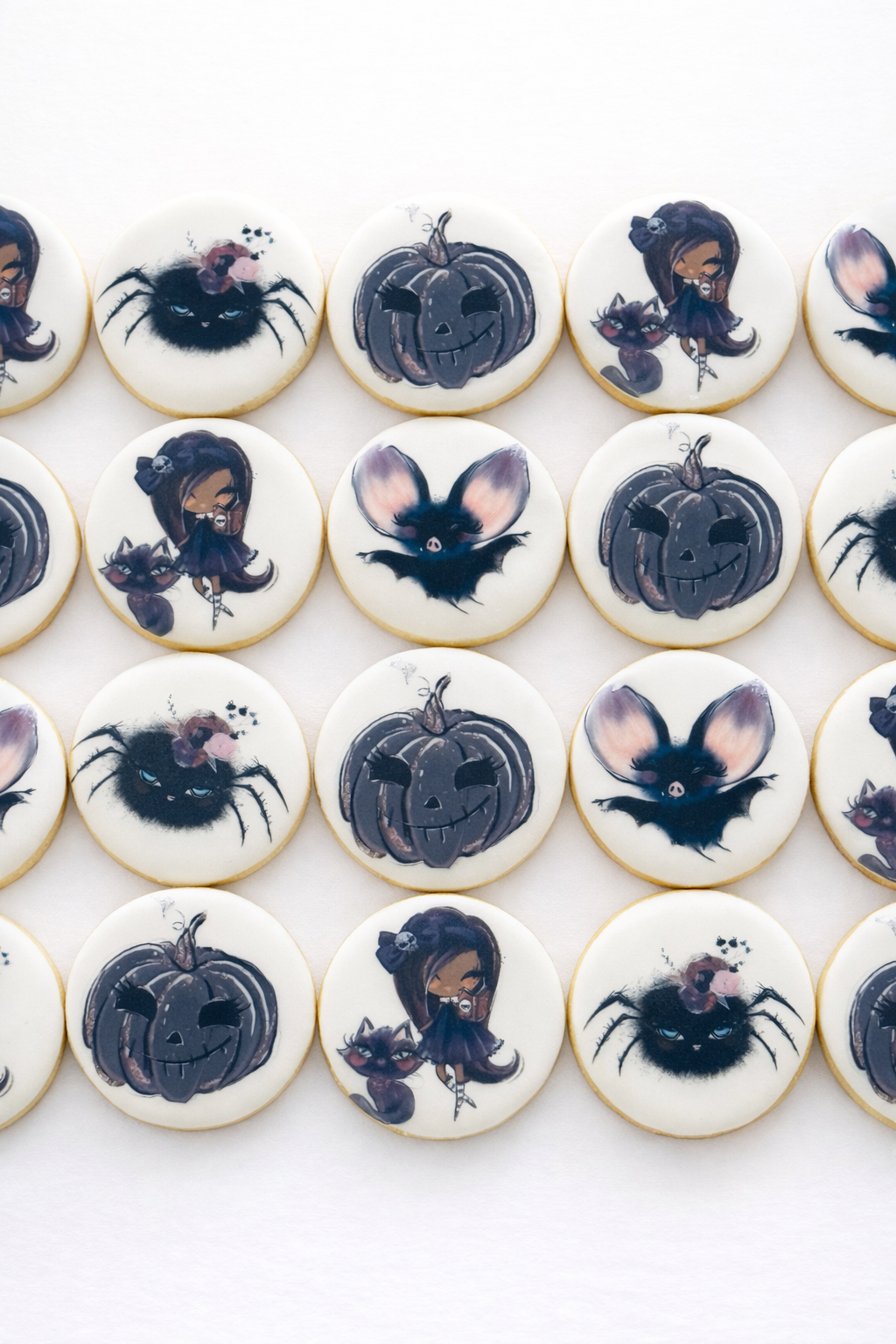 Halloween-themed decorated cookies with images of a bat, pumpkin, and witch.