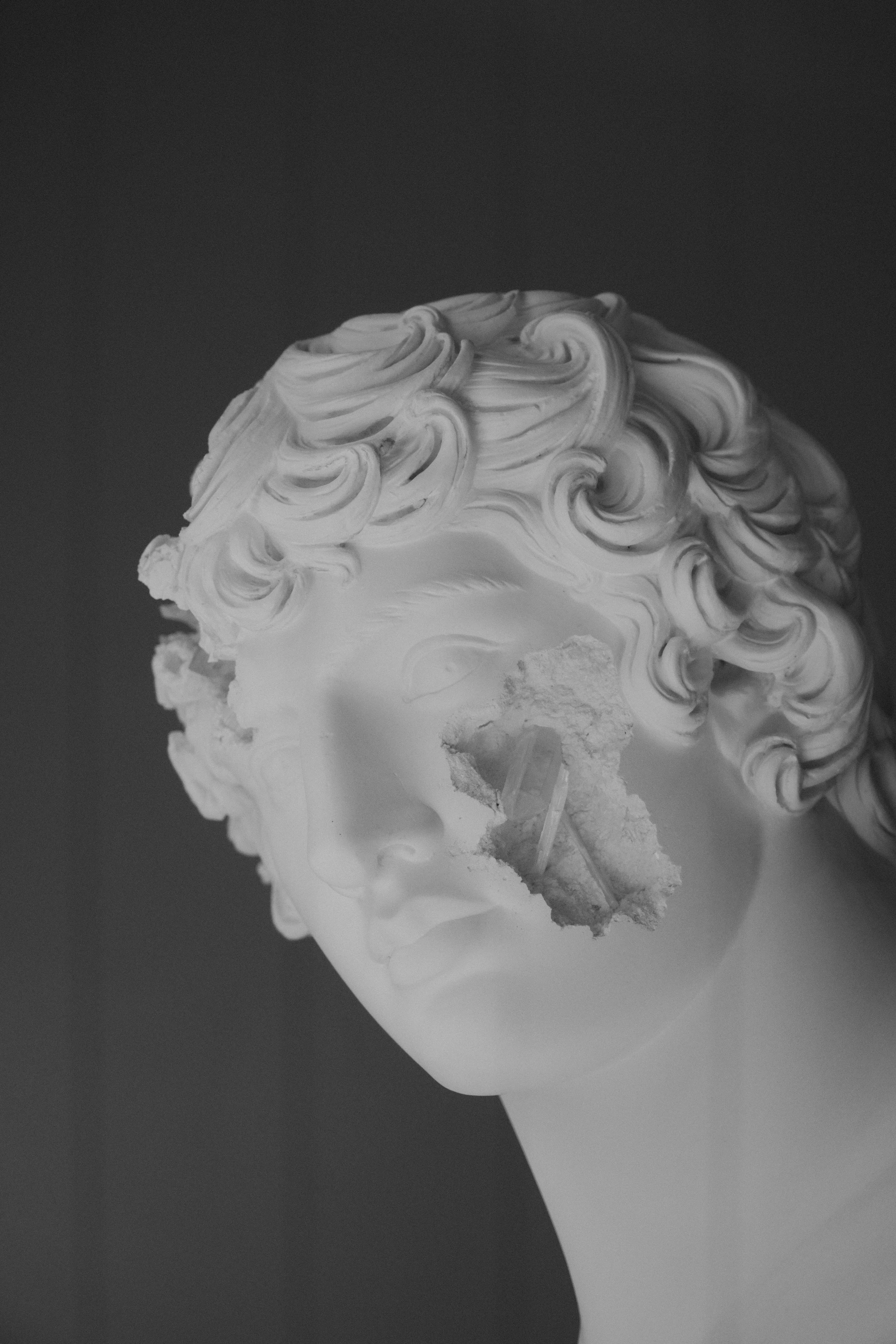 Verwitterte antike Skulptur eines menschlichen Kopfes mit Verletzungen