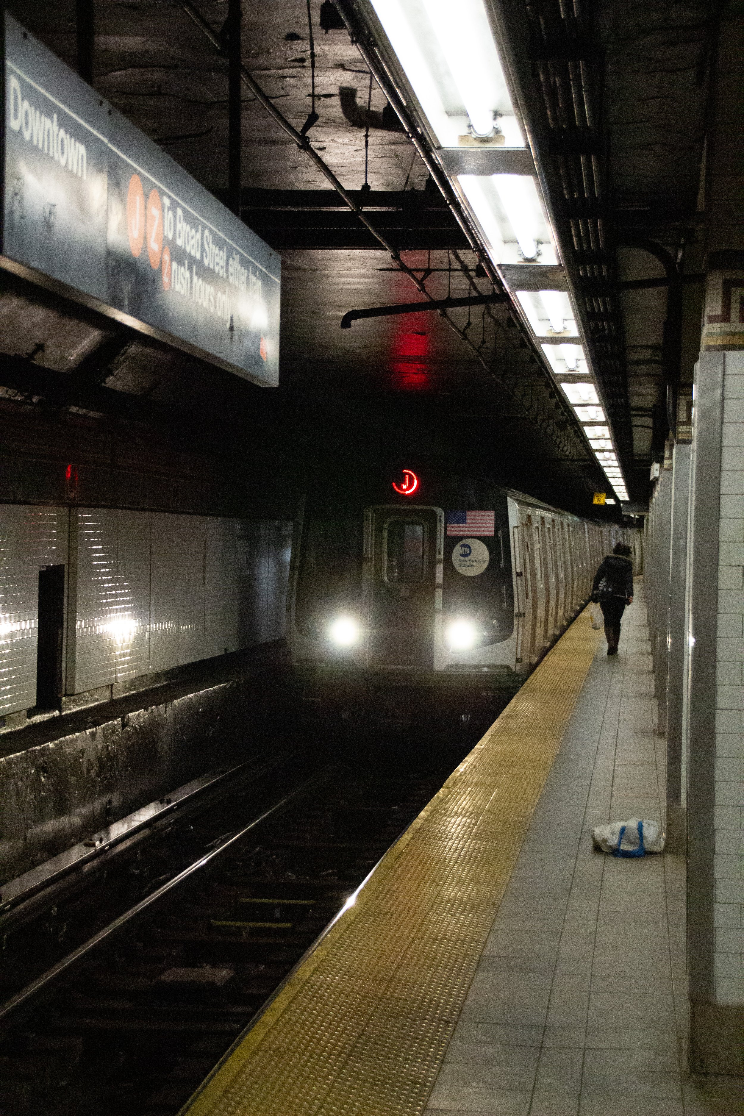 Ein U-Bahn Zug im U-Bahn-Station in New York City, mit einem ankommenden Zug in der Dunkelheit der Tunneln, eine Person läuft auf dem Bahnsteig.