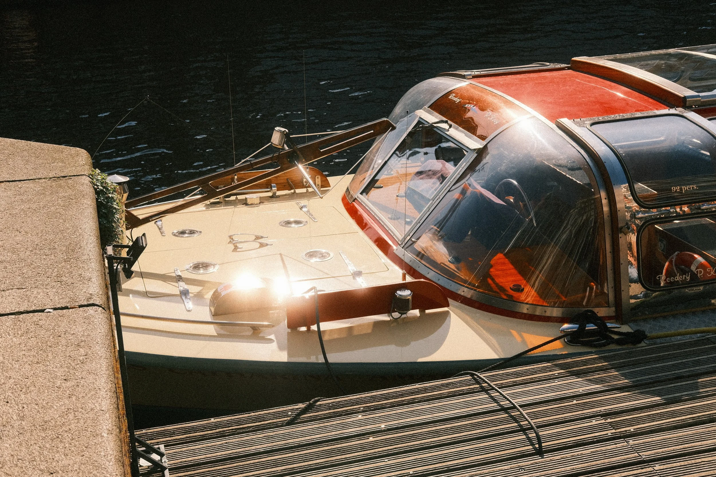 Ein historisches Boot, das an einem Steg im Wasser festgemacht ist, mit einer durchsichtigen Kuppel über dem Cockpit und mehreren Instrumenten auf dem Deck, bei Sonnenlicht fotografiert.