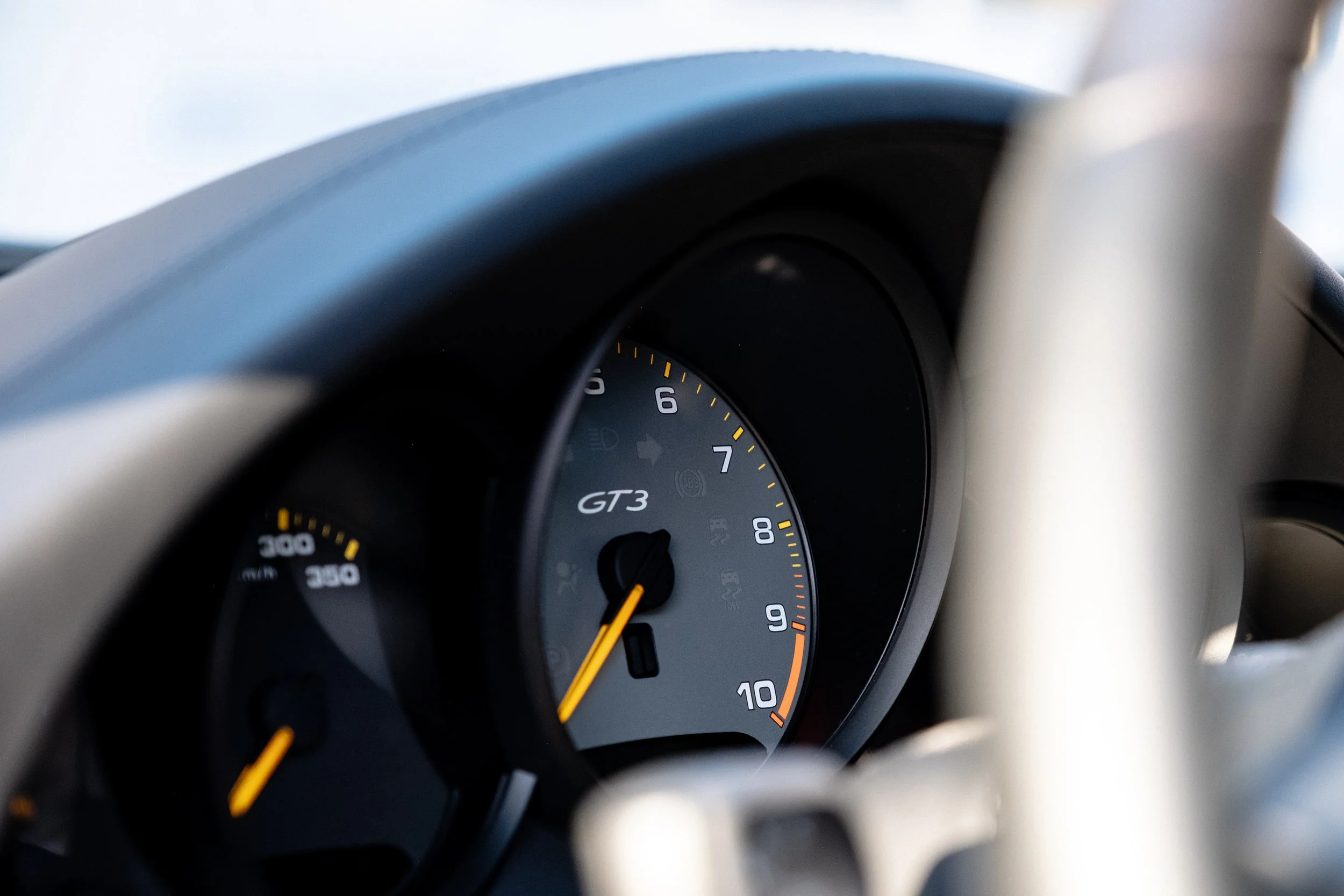Nahaufnahme des Tachos im Cockpit eines Porsche GT3, zeigt die Drehzahlmesser bei circa 1.5. Man sieht das Armaturenbrett im Innenraum mit Fokus auf das Instrumentencluster.