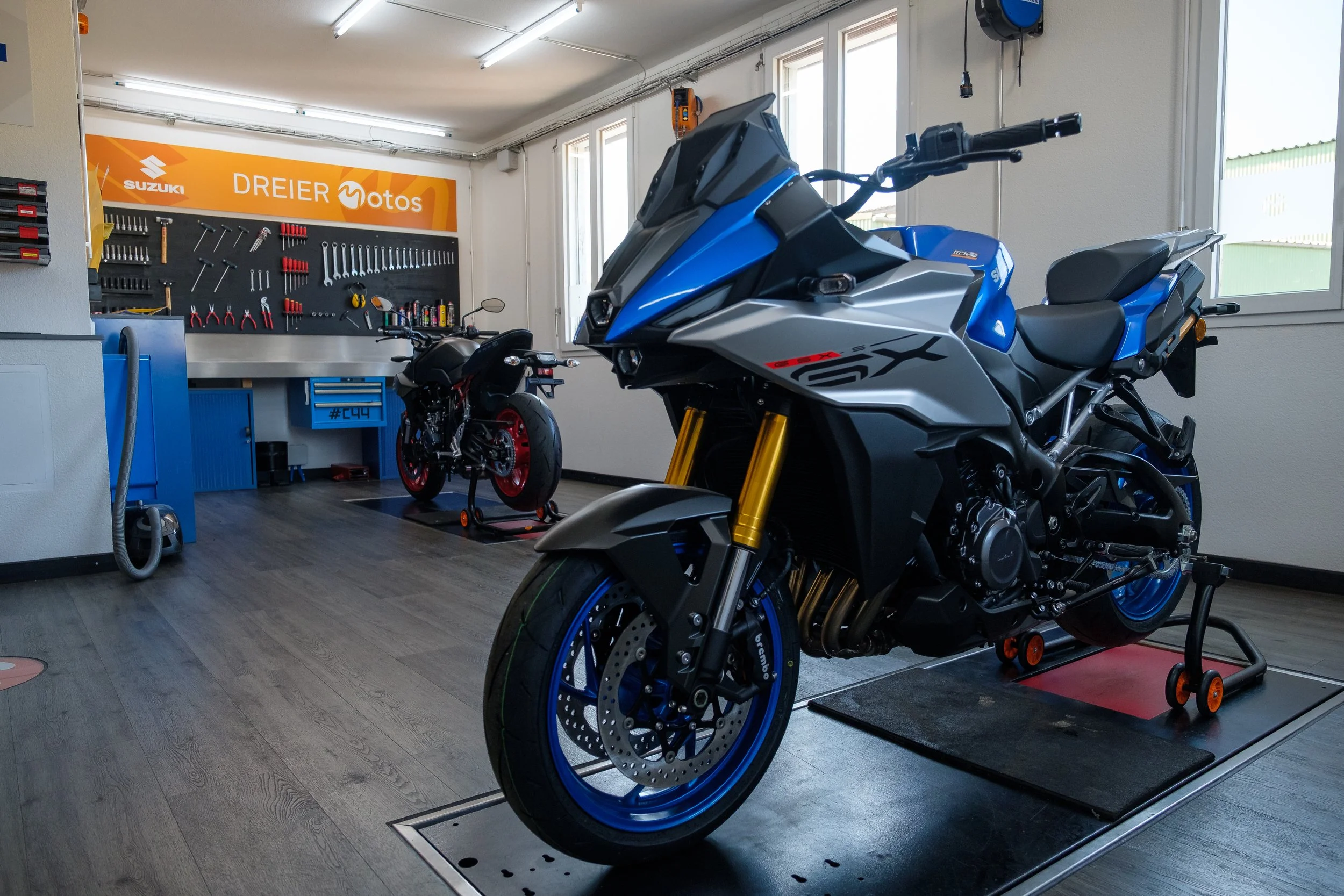 Motorrad in Werkstatt mit Werkzeugen an der Wand im Hintergrund.